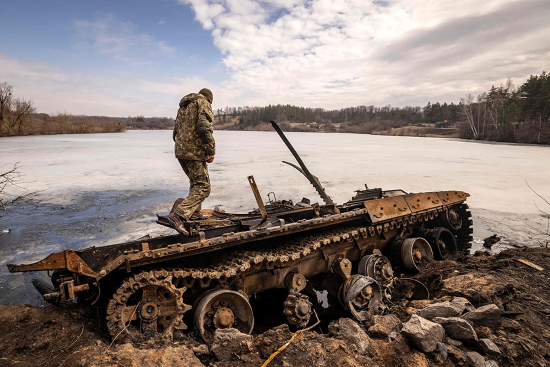 <p>A Ukrainian serviceman stands near a destroyed Russian tank in the northeastern city of Trostianets, on March 29, 2022</p>
