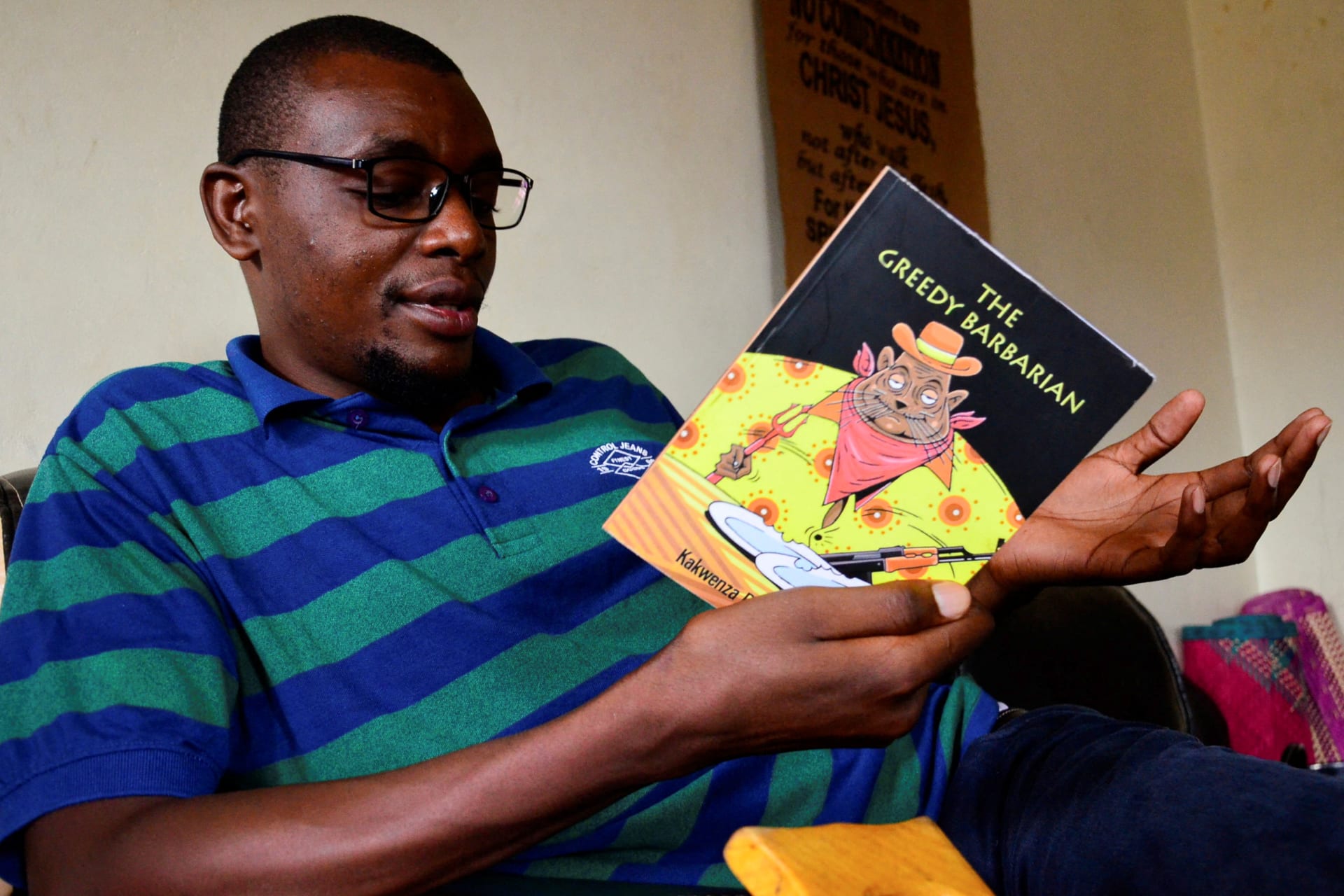 <p>Ugandan author of “Greedy Barbarian” Kakwenza Rukirabashaija reads the book at his home in Iganga district in Eastern Uganda on May 11, 2020.</p>

