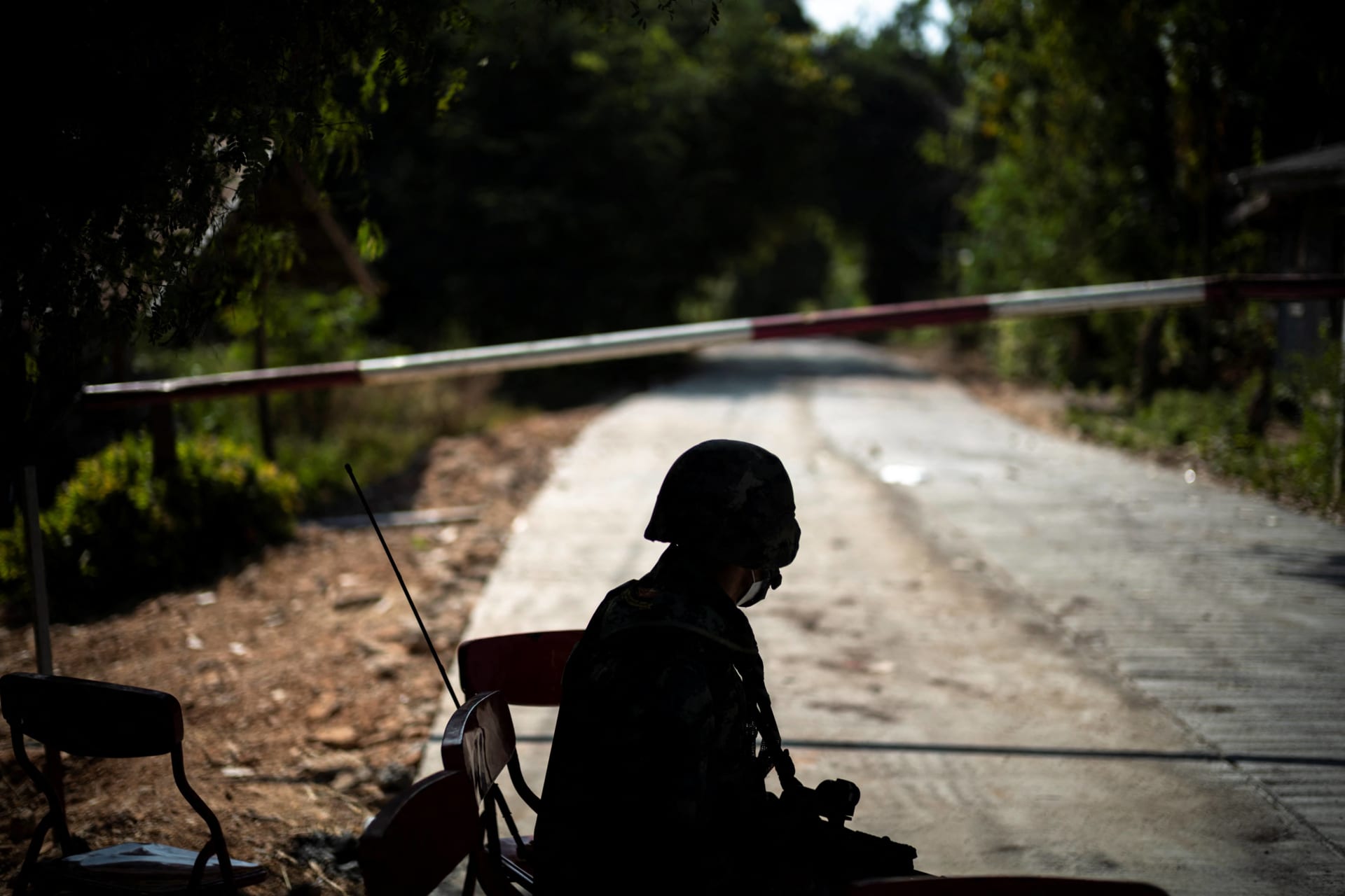 <p>A Thai soldier sits in front of the blockage of a road leading to the Thailand-Myanmar border where the fighting between the Myanmar army and ethnic minority rebels still continues, in Mae Sot district, Tak province, Thailand, on December 19, 2021.</p>
