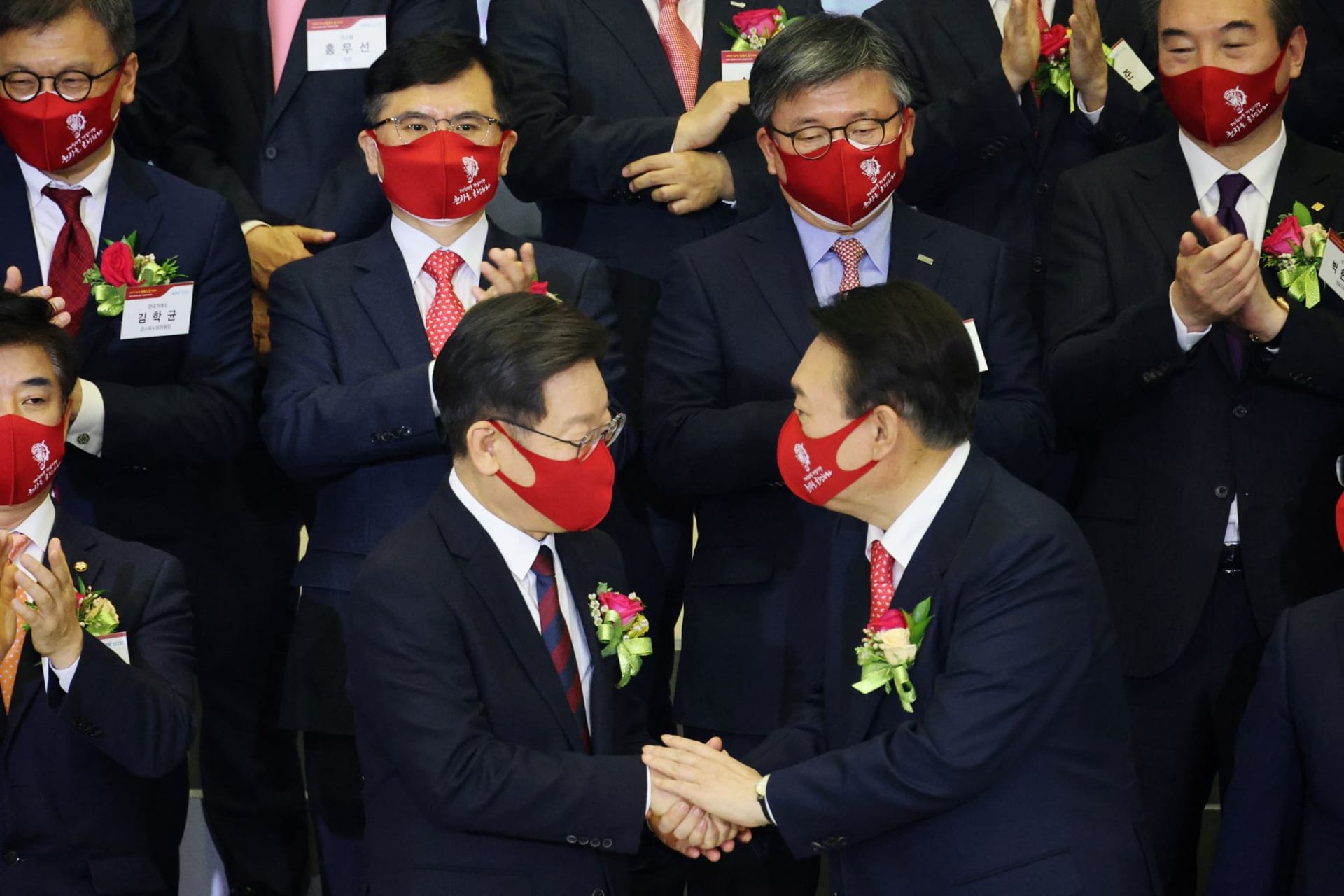 <p>Yoon Seok-youl, the presidential election candidate of South Korea’s main opposition People Power Party, shakes hands with Lee Jae-myung, the presidential election candidate of the ruling Democratic Party, in Seoul, South Korea on January 3, 2022.</p>
