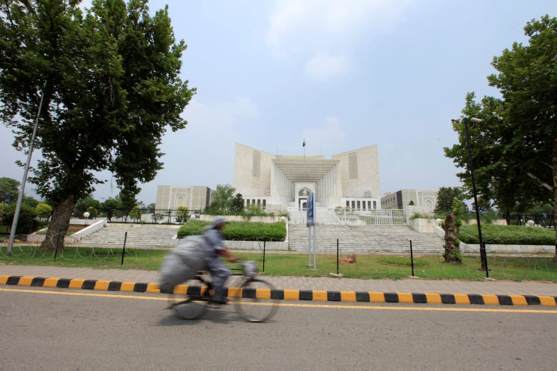 <p>A man rides a bicycle past the Supreme Court building in Islamabad.</p>