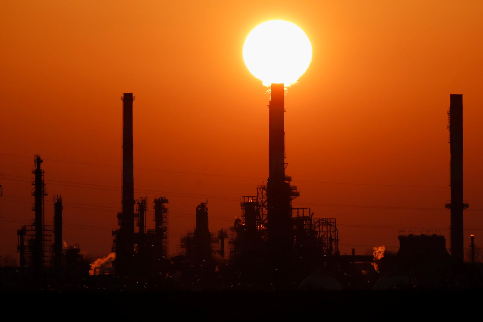 <p>The sun sets behind the chimneys of the Total Grandpuits oil refinery, southeast of Paris, France, March 1, 2021.</p>

