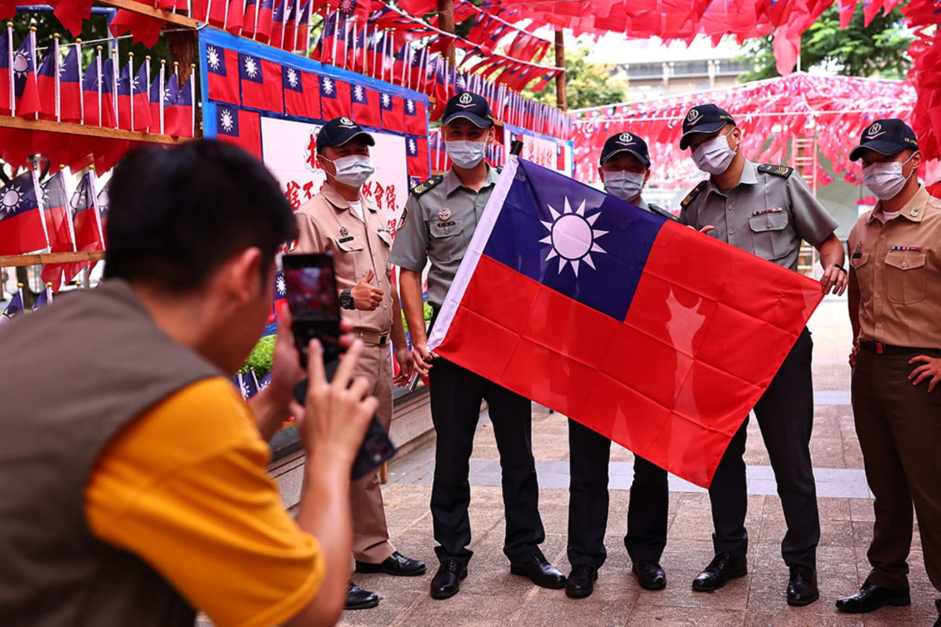 <p>A group of soldiers takes photos at a square decorated with Taiwan flags</p>
