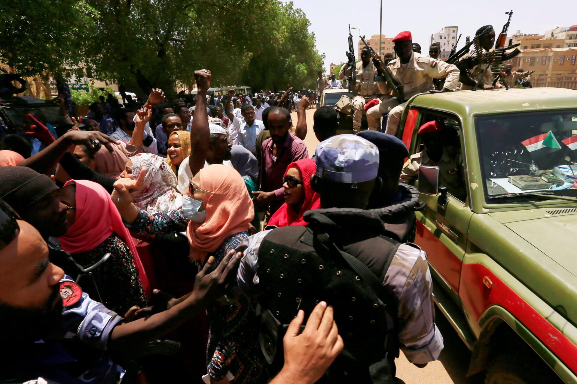 <p>Sudanese citizens attempt to cross a police blockade as they chant slogans outside a court during the trial against ousted President Omar al-Bashir and his former allies on charges of leading a 1989 military coup in Khartoum, Sudan on September 1, 2020.</p>
