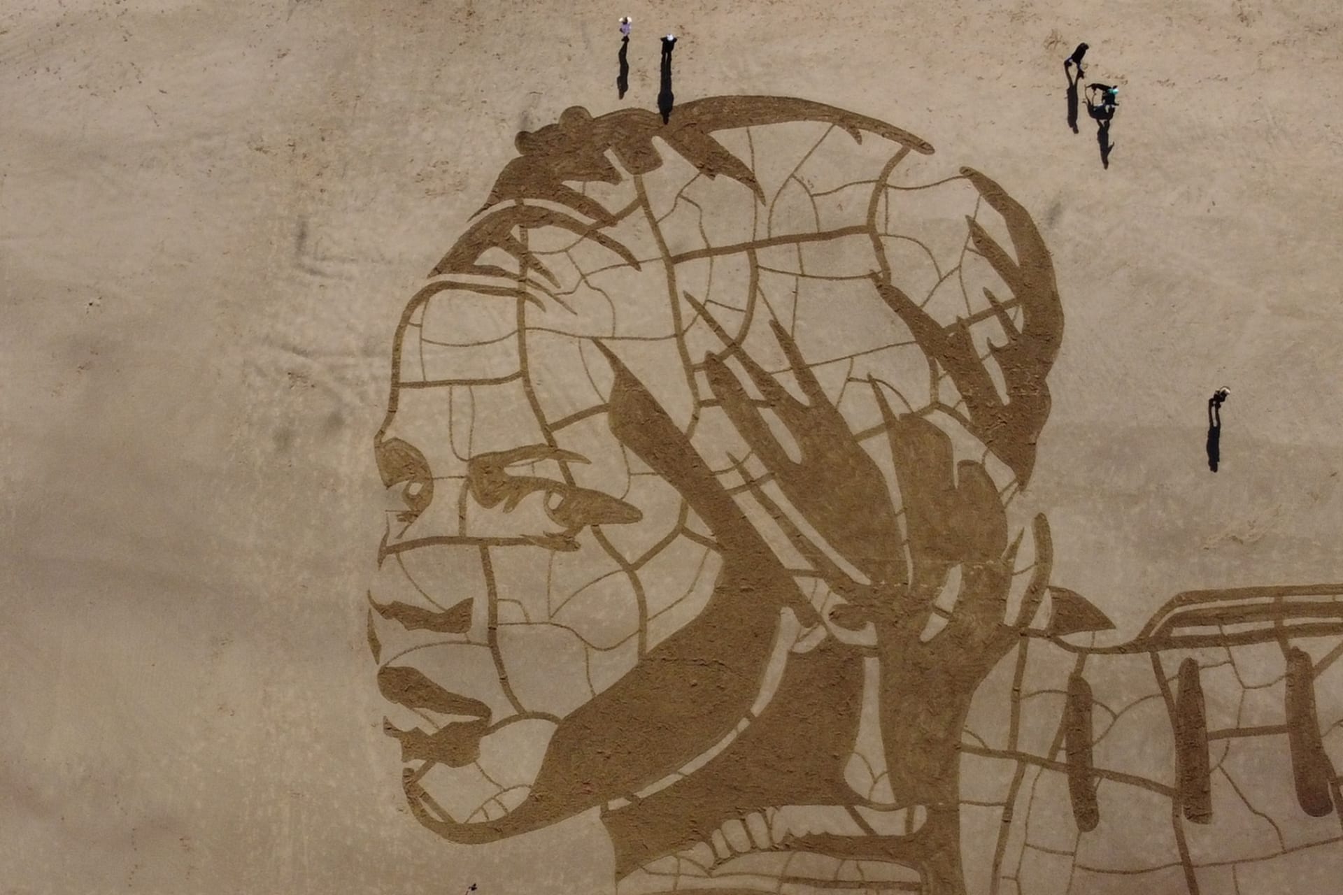 <p>WaterAid and Sand In Your Eye’s giant sand drawing, seen on Whitby Beach, Britain, shows a child carrying water on dry, cracked ground next to the rising tide to highlight the effect of climate change on people’s access to water on March 15, 2021.</p>
