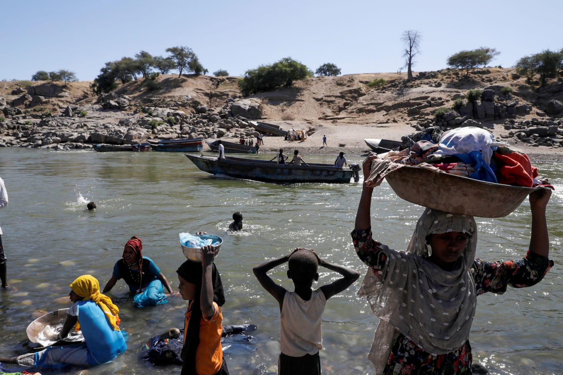 <p>Refugees stand on the Ethiopian bank of a river that separates Sudan from Ethiopia near the Hamdeyat refugees transit camp, which houses Ethiopian refugees fleeing the fighting in the Tigray region, on the Sudan-Ethiopia border on November 30, 2020. </p>

