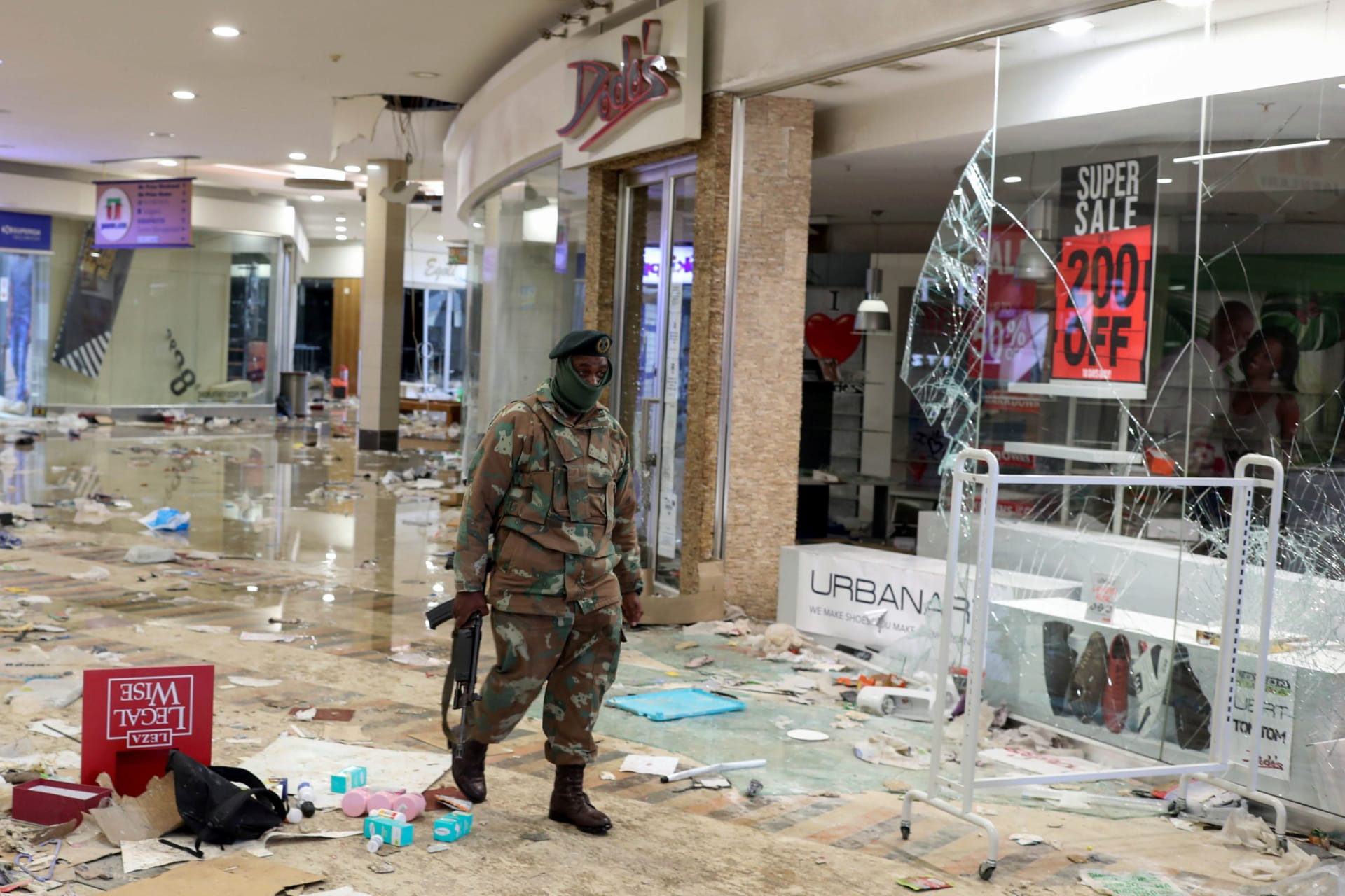<p>A member of the military walks as he inspects the damage at the looted Jabulani mall as the country deploys army to quell unrest linked to jailing of former President Jacob Zuma, in Soweto, South Africa on July 13, 2021.</p>
