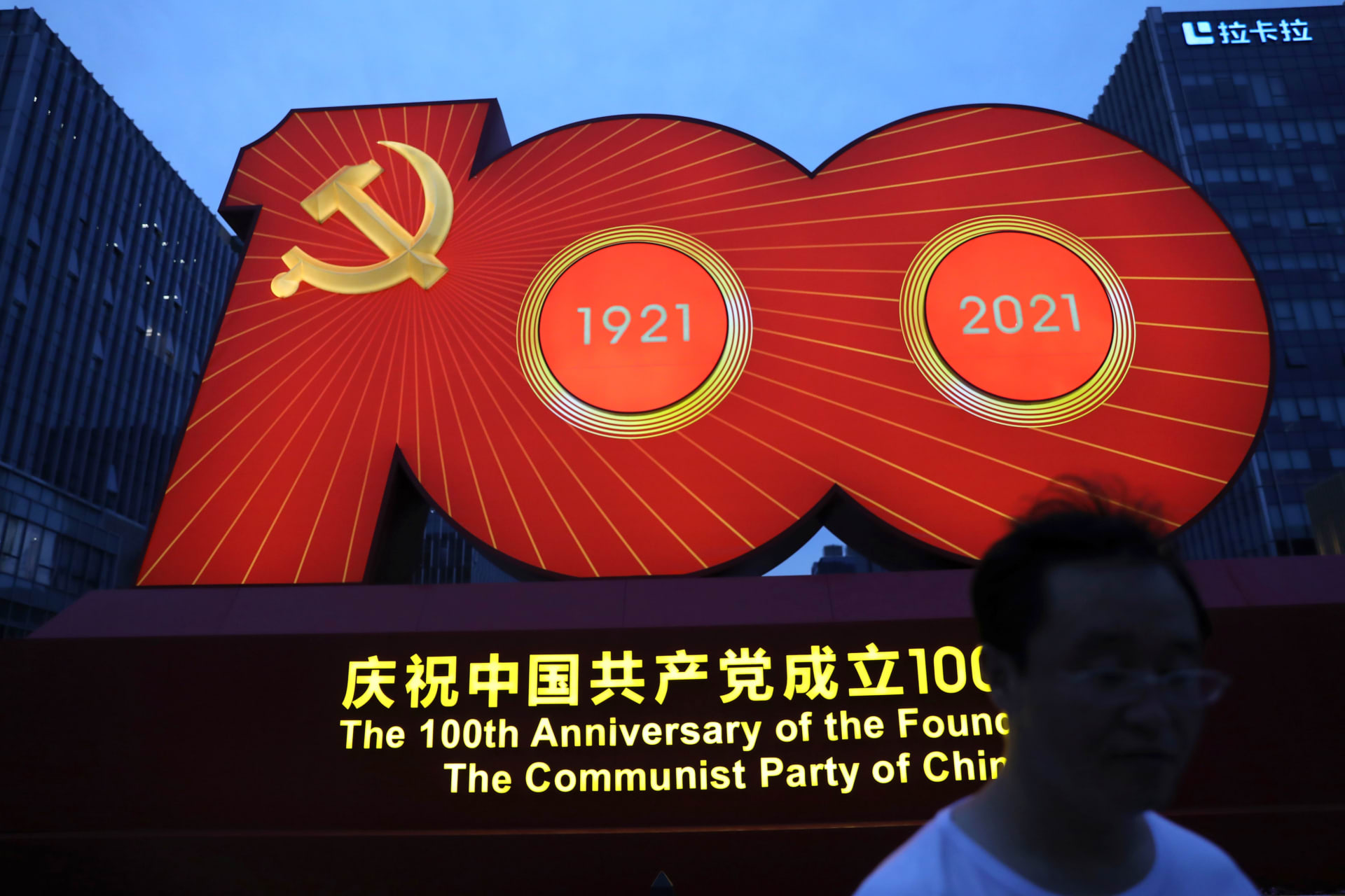<p>A man walks past a light installation marking the one hundredth founding anniversary of the Communist Party of China at a hi-tech industrial park, in Beijing, China on June 23, 2021.</p>
