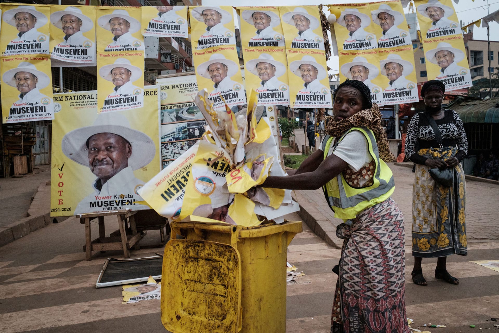 <p>A worker throws away campaign posters of Ugandan President Yoweri Museveni.</p>
