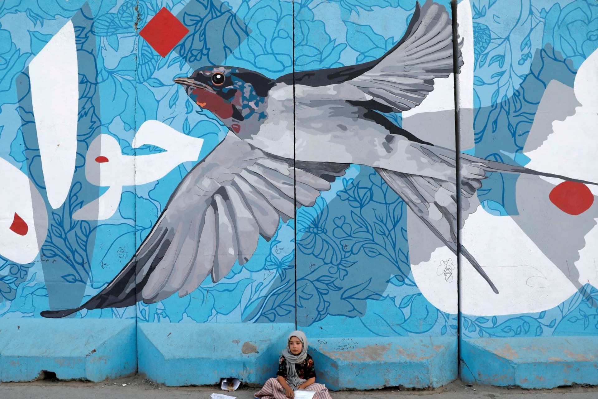 <p>A young shoe polisher waits for customers beneath a mural in Kabul, Afghanistan.</p>
