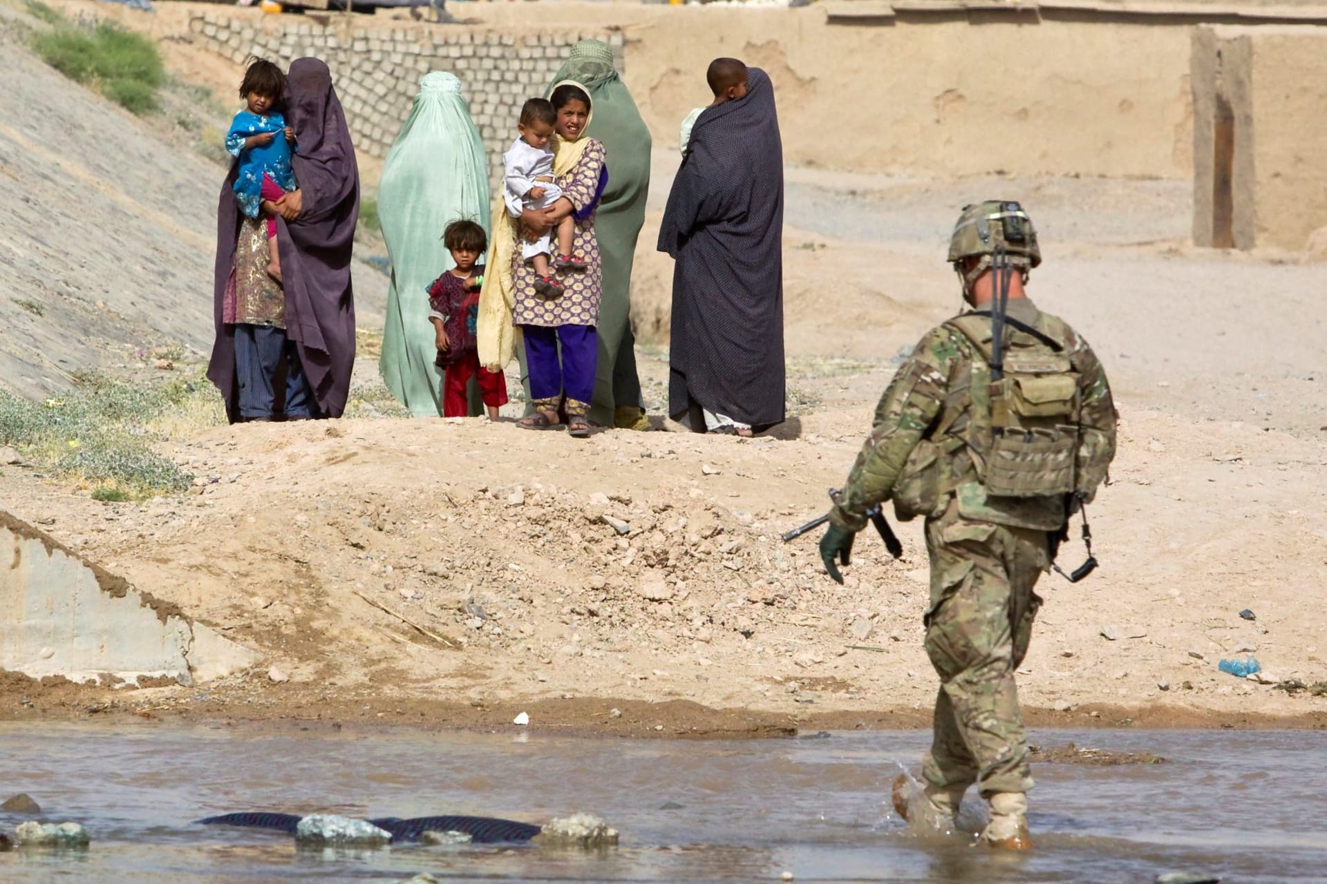 <p>A U.S. Army soldier walks toward Afghan women with children.</p>
