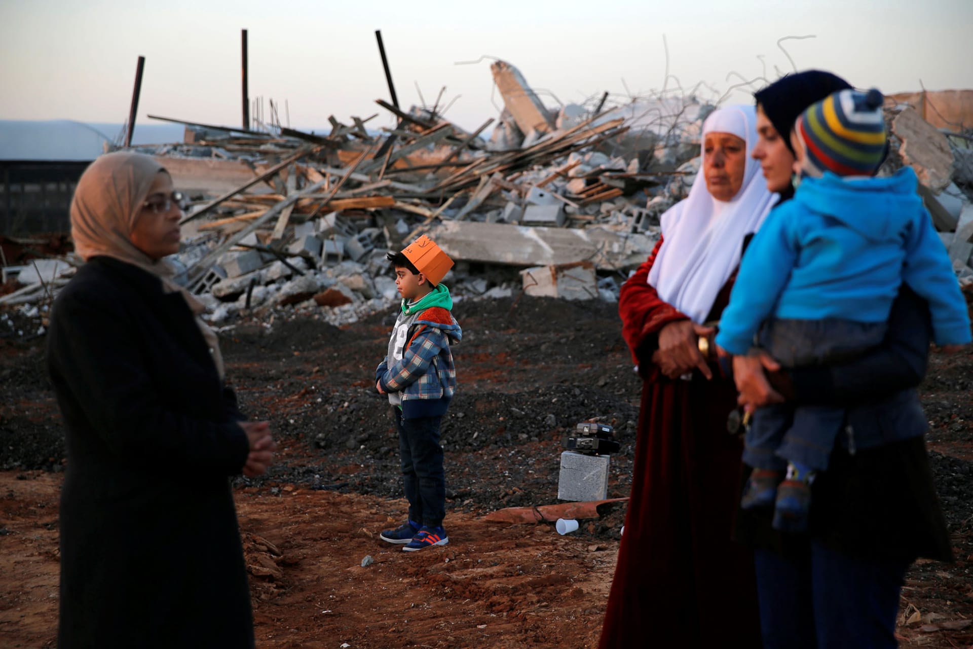 <p>Arab citizens of Israel stand near demolished houses in the northern city of Qalansawe.</p>

