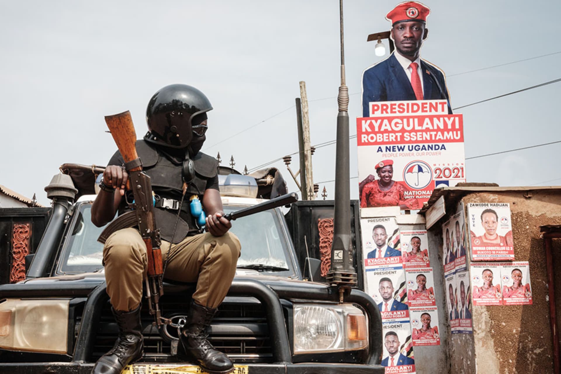 <p>A police officer sits on a car at the headquarters of the National Unity Platform in Kampala, Uganda, in January 2021.</p>
