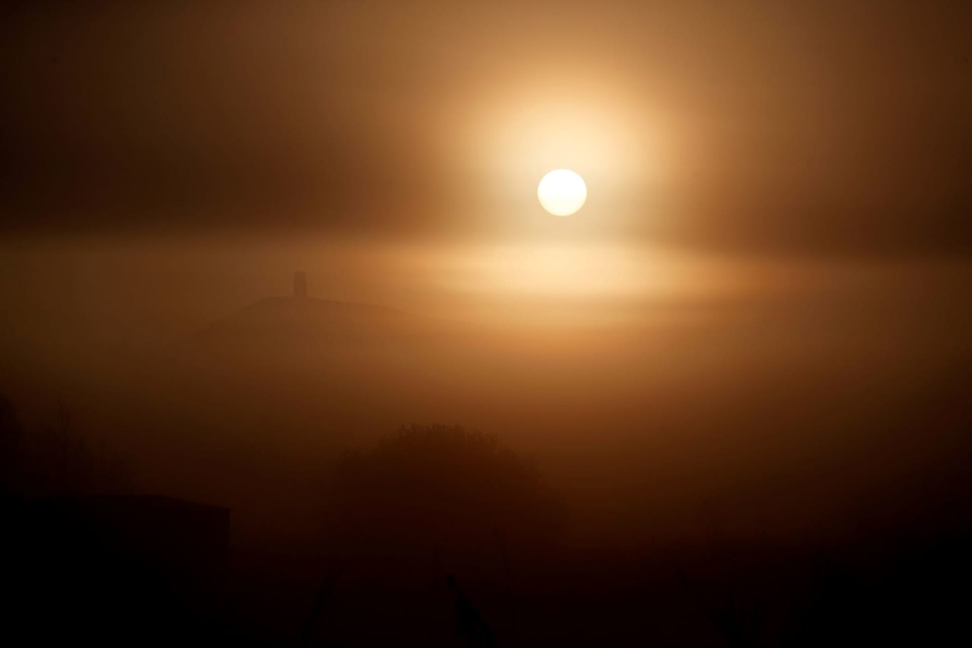 <p>The sun rises behind Saint Michael’s Church and Glastonbury Tor, in Glastonbury, Britain on November 4, 2020. </p>
