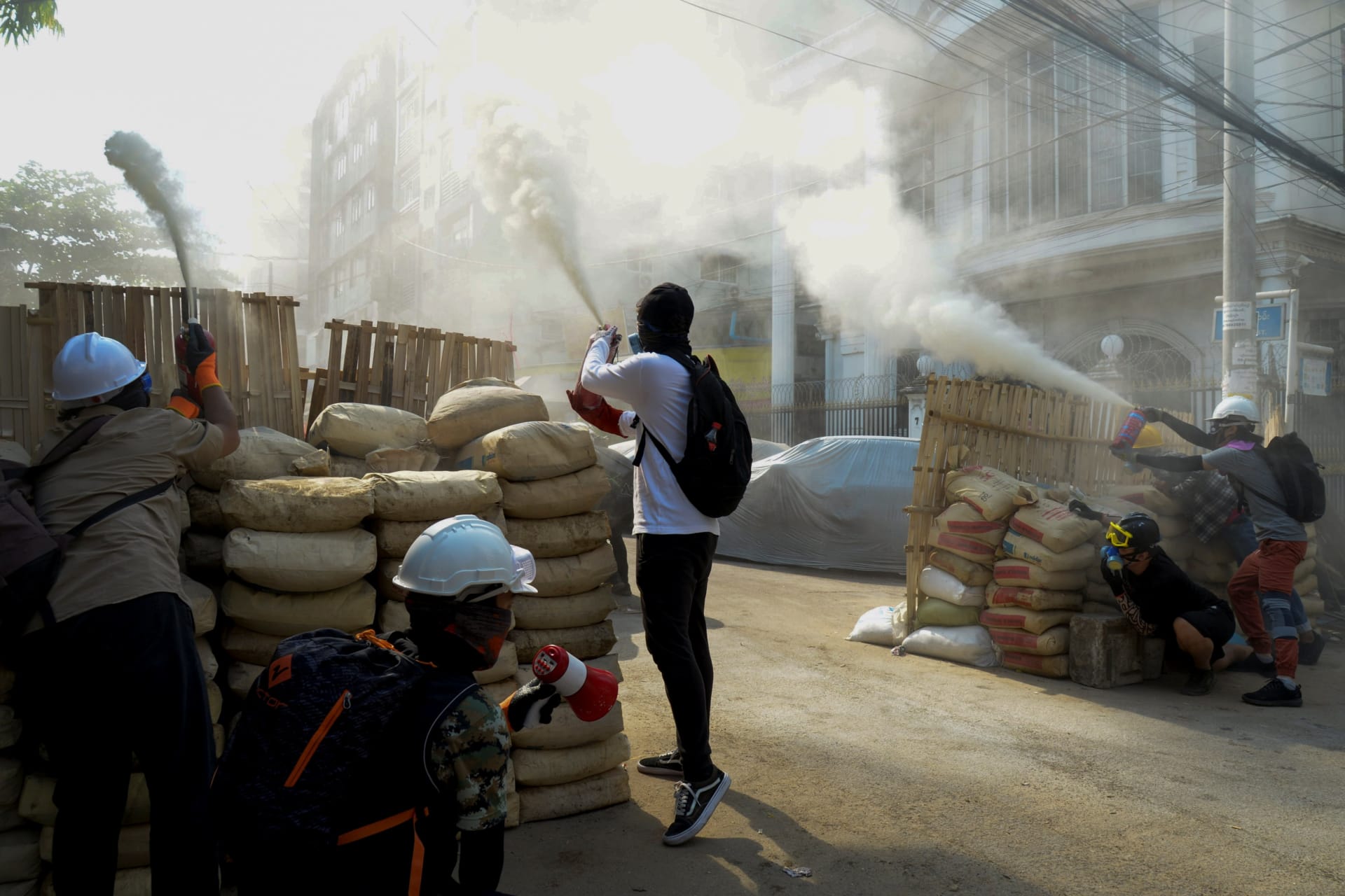 <p>Anti-coup demonstrators sprays fire extinguishers over a barricade during a protests in Yangon, Myanmar, on March 9, 2021.</p>