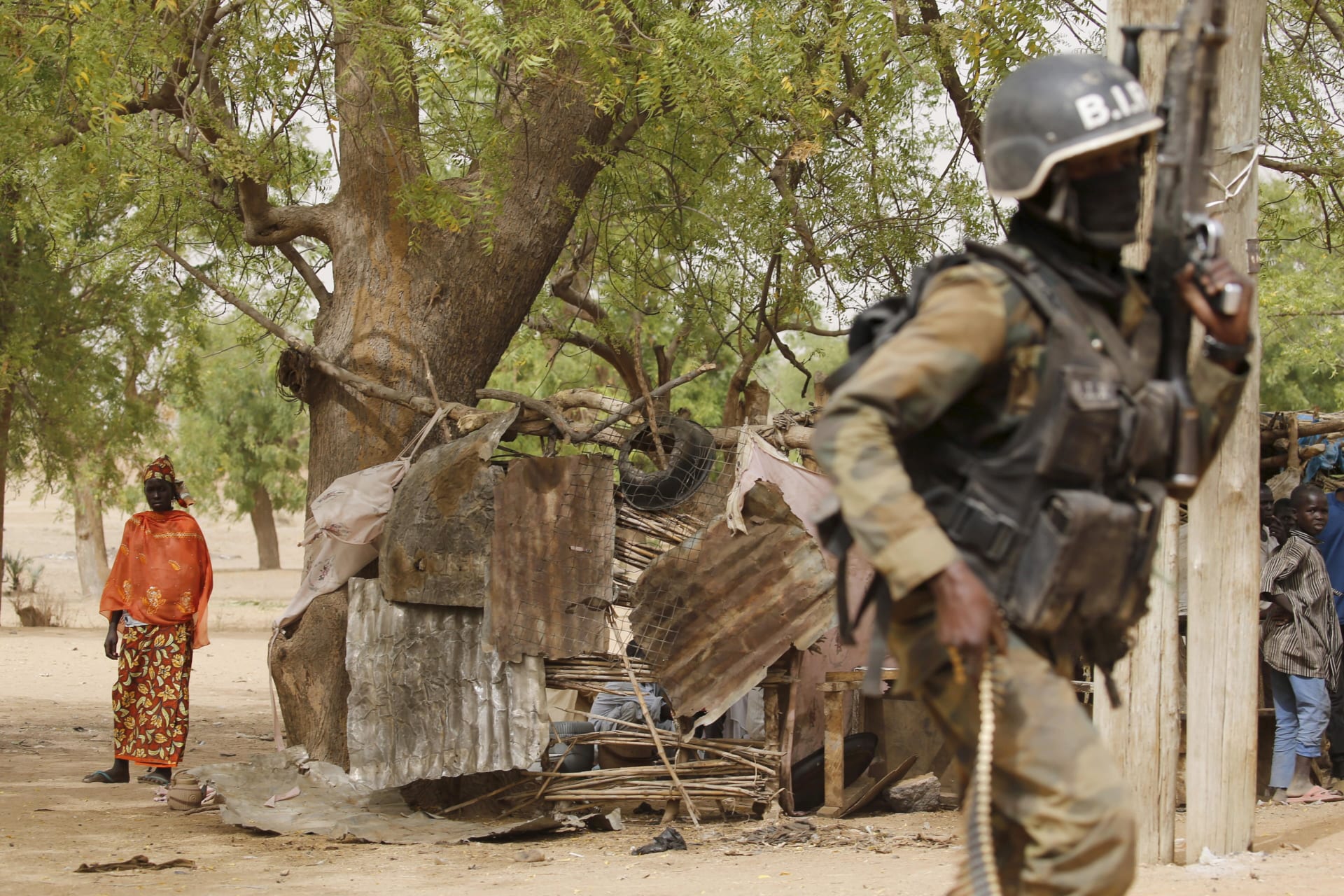 <p>A woman watches a Cameroonian soldier from the Rapid Intervention Brigade on patrol in Kolofata, Cameroon on March 16, 2016.</p>
