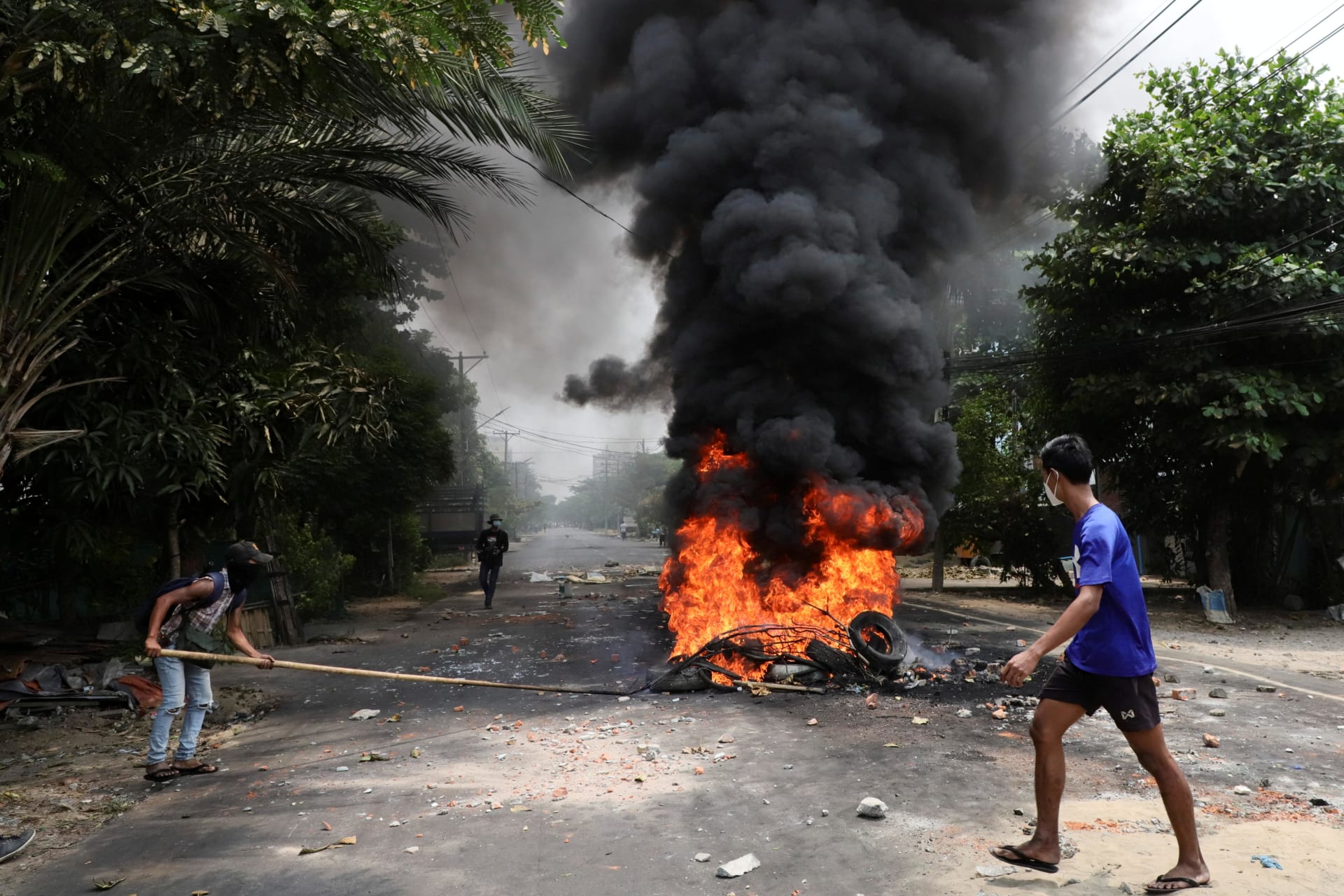 <p>An anti-coup protester walks past burning tires after activists launched a “garbage strike” against the military rule, in Yangon, Myanmar March 30, 2021.</p>
