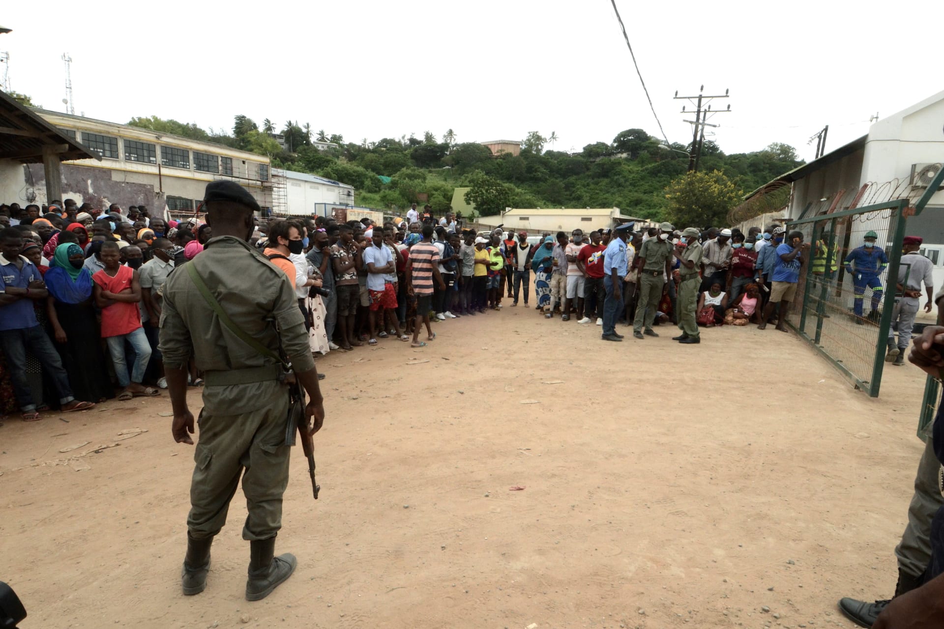 <p>Security officials stand guard as people wait for friends and relatives as a ship carrying more than 1,000 people fleeing an attack claimed by Islamic State-linked insurgents on the town of Palma, docks in Pemba, Mozambique on April 1, 2021.</p>
