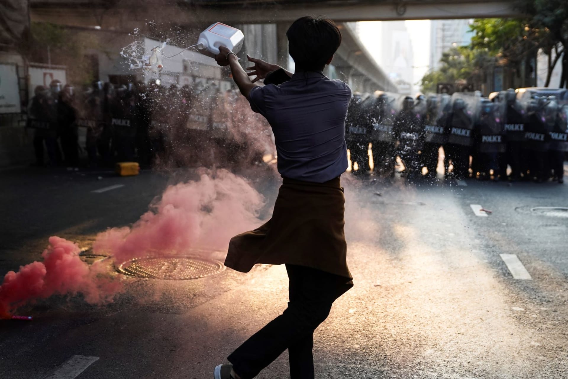 <p>Anti-Thai government protester throws a liquid during a clash with riot police after protesters showed up at a rally for Myanmar’s democracy outside the embassy, in Bangkok, Thailand on February 1, 2021. </p>
