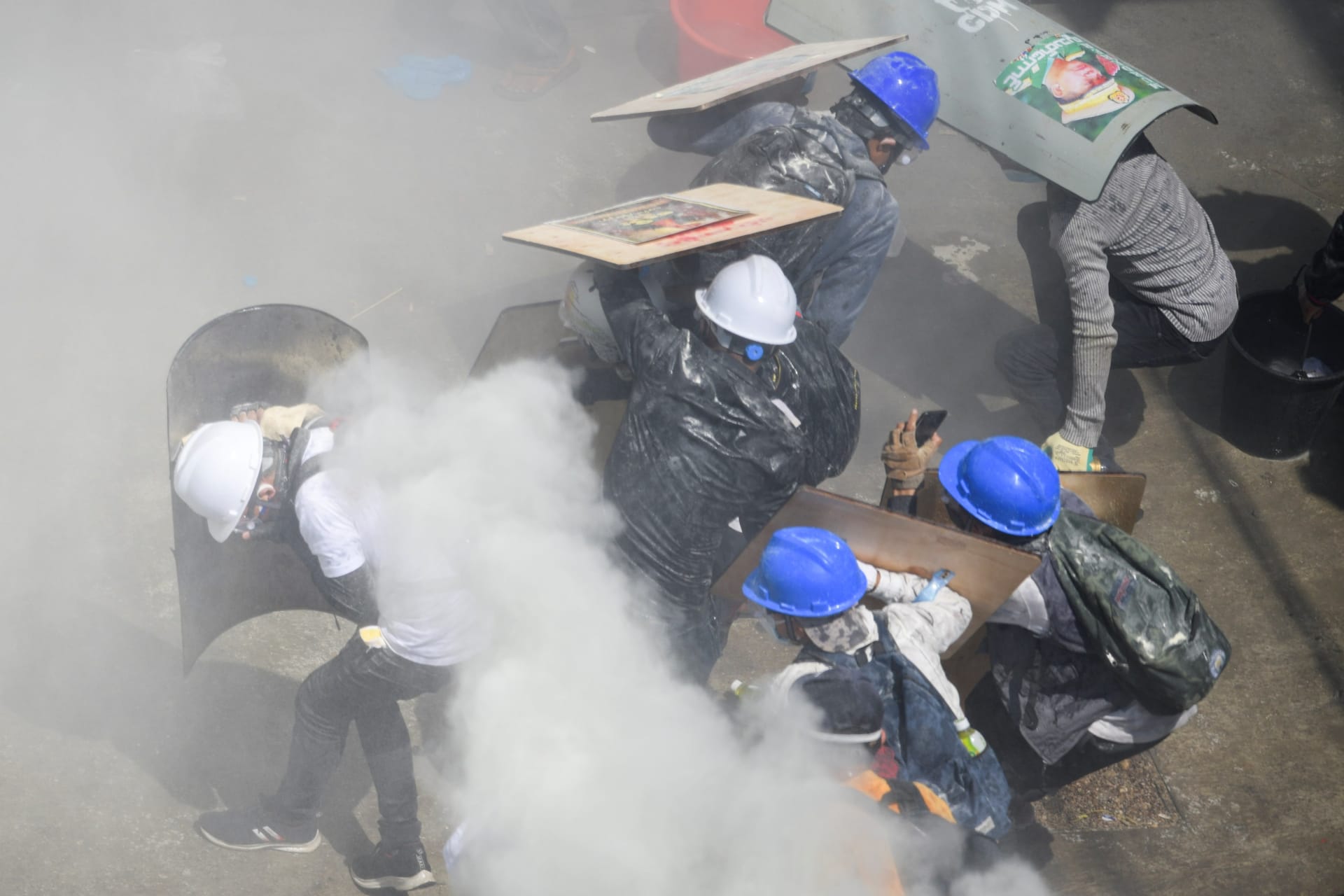 <p>Protesters take shelter behind shields as they clash with riot police officers during a protest against the military coup in Yangon, Myanmar, on March 1, 2021.</p>