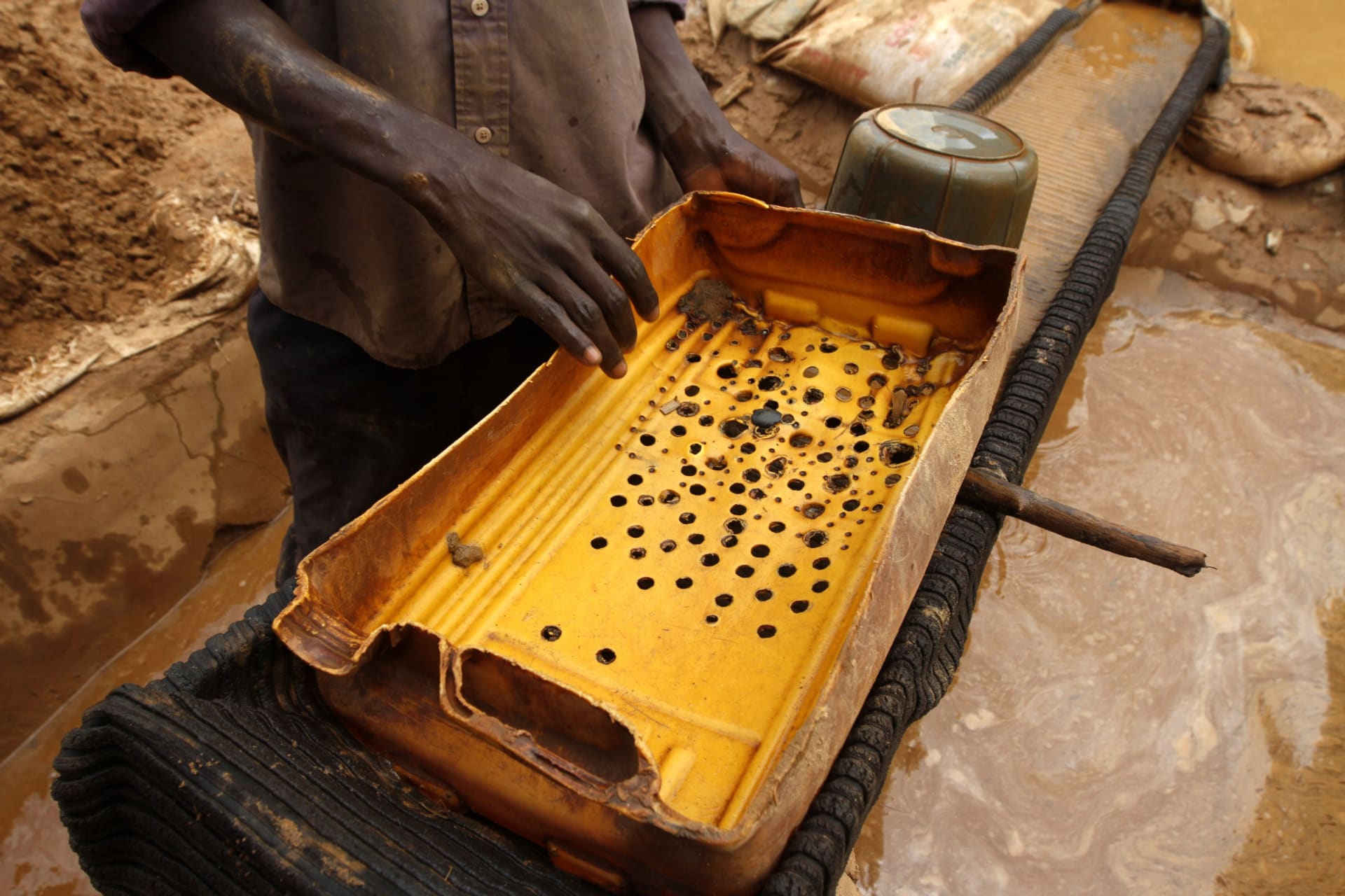 <p>A man holds a plastic filter as he prepares to wash gold dust at a local goldmine in Bagega village in the northwestern state of Zamfara on August 14, 2013.</p>
