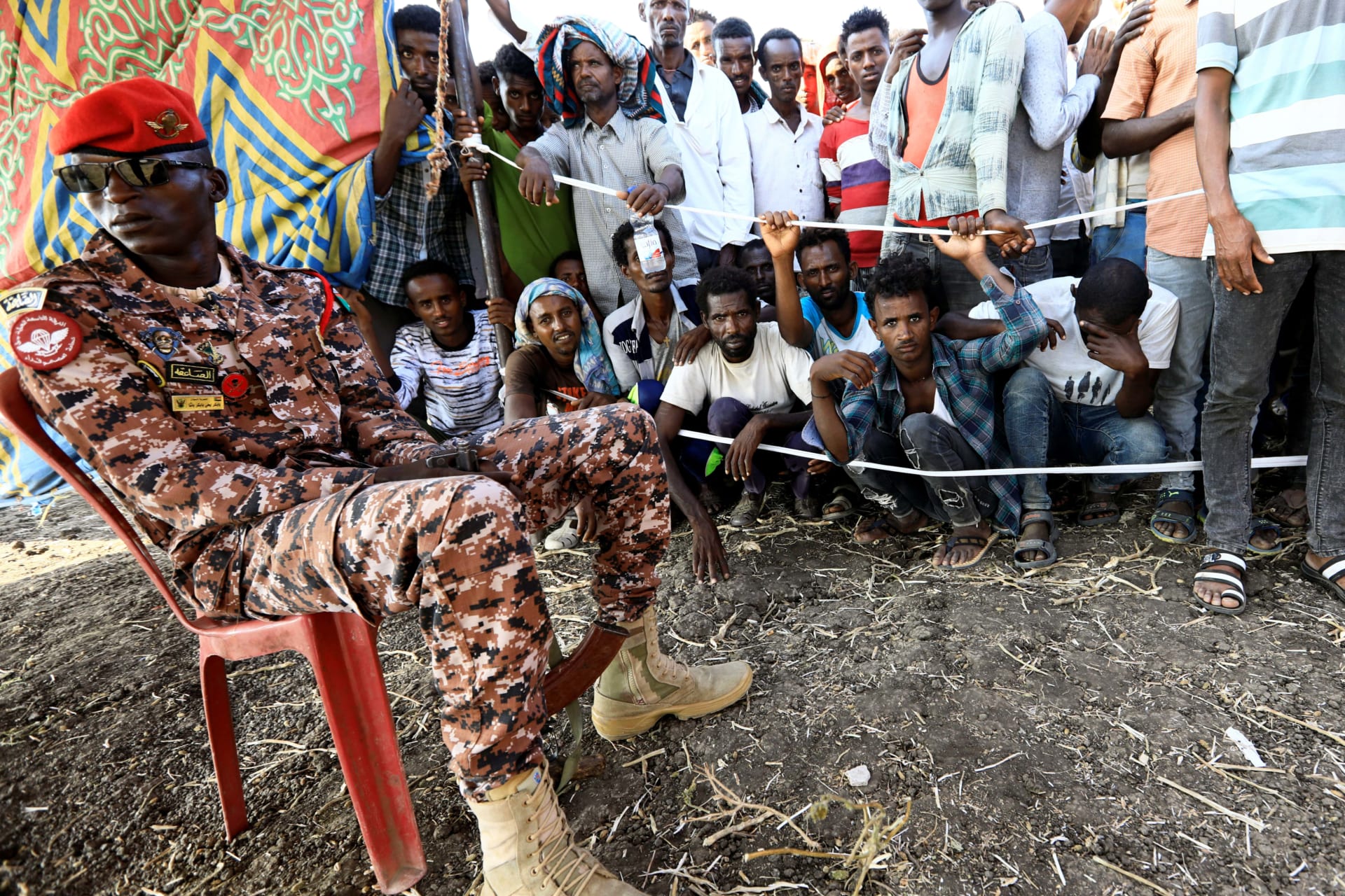 <p>A Sudanese military officer keeps guard as Ethiopians who fled war in Tigray region, gather to receive relief supplies from the World Food Programme at the Fashaga camp on the Sudan-Ethiopia border in Al-Qadarif state, Sudan November 20, 2020.</p>
