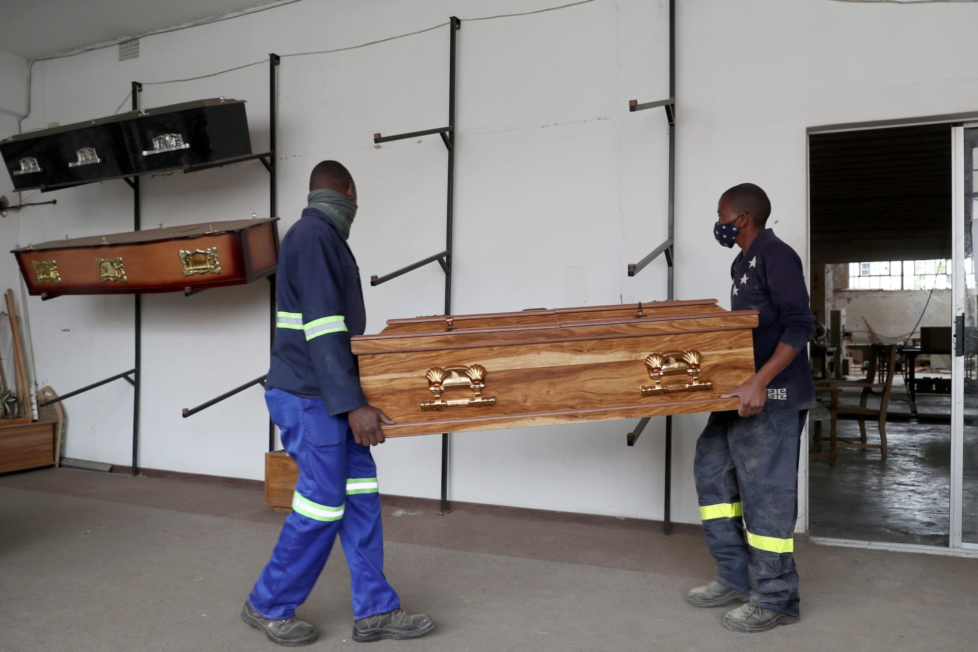 <p>Workers carry a coffin to the display area at the Kingsize Coffins manufacturing plant, amid a nationwide coronavirus disease (COVID-19) lockdown, in Benoni, South Africa on January 25, 2021.</p>
