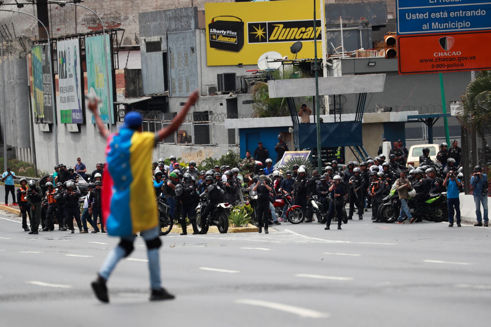 <p>A demonstrator covered with a Venezuelan flag gestures in front of security forces during a protest in Caracas, Venezuela, on March 10, 2020.</p>
