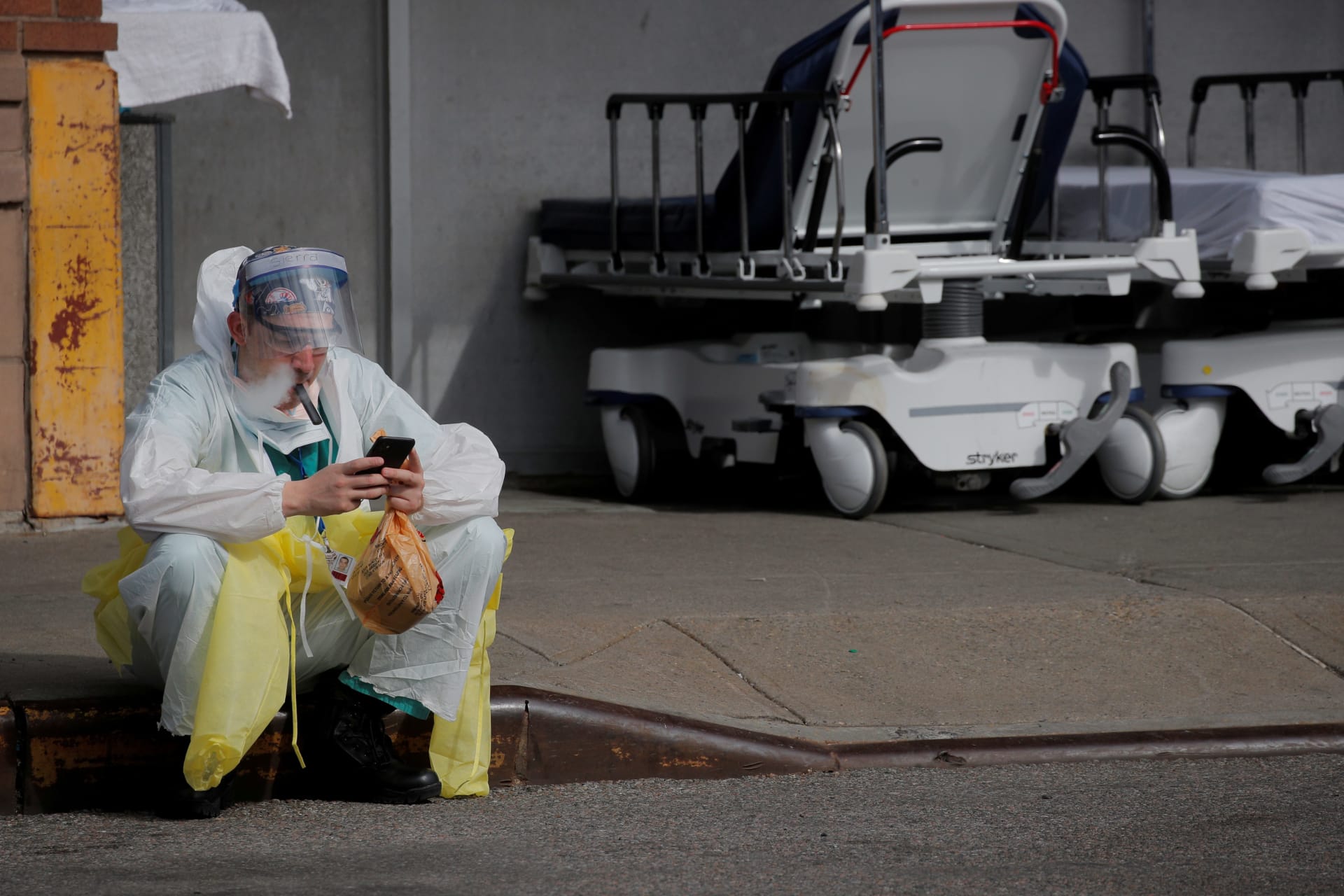 <p>A healthcare worker sits on the curb as he uses a vaping device while taking a break outside Maimonides Medical Center.</p>
