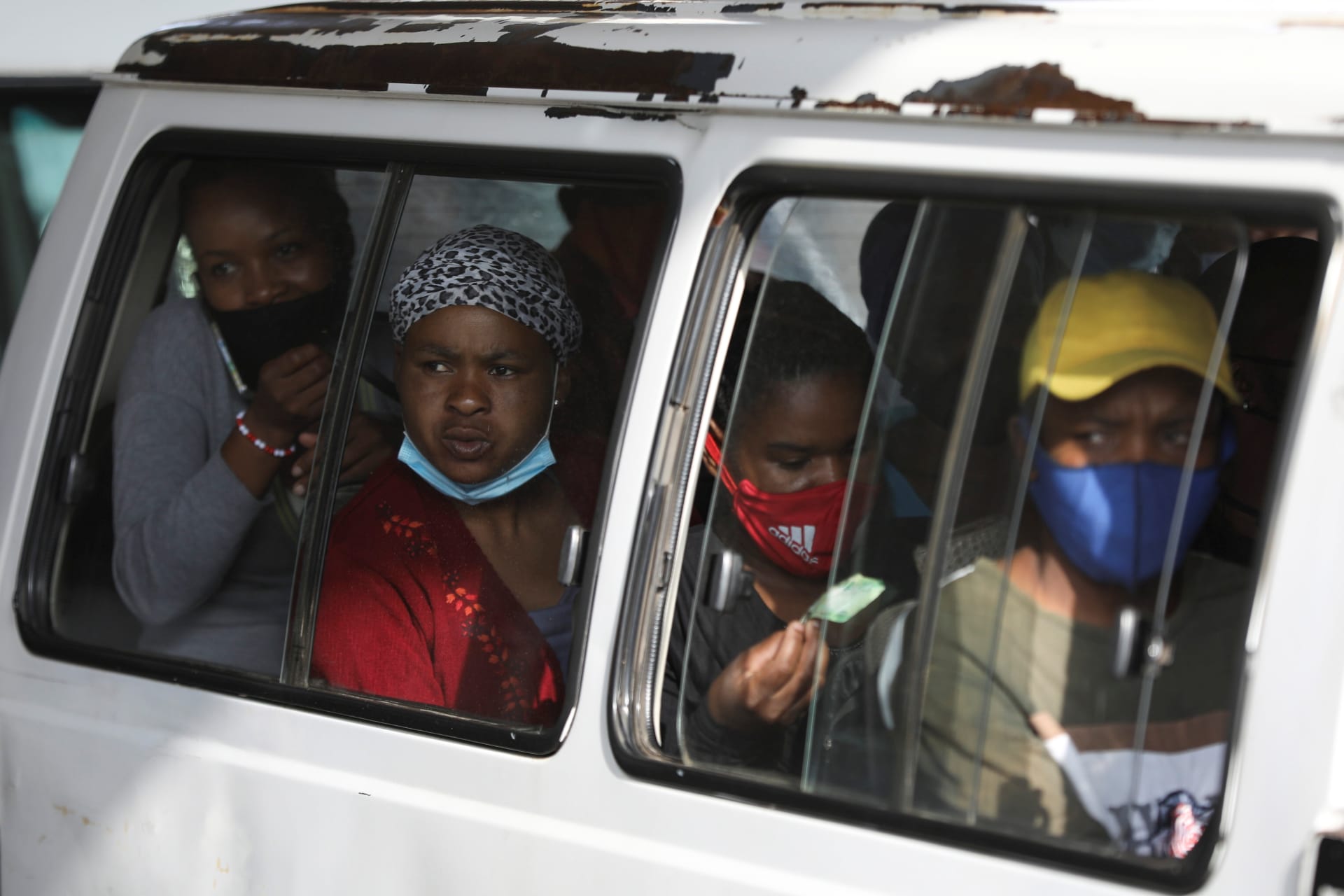 <p>Commuters, some wearing face masks, look on through a window at the Baragwanath taxi rank, amid the coronavirus disease (COVID-19) outbreak, in Soweto, South Africa on December 29, 2020.</p>
