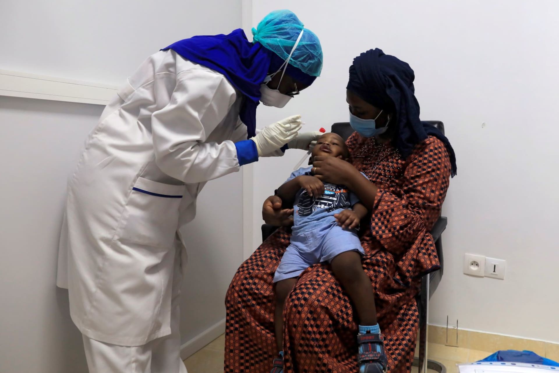 <p>A healthcare worker wearing protective gear takes a swab sample from a boy to test him for the coronavirus disease (COVID-19) at an Institute for Health Research, Epidemiological Surveillance and Training (IRESSEF) testing center, in Dakar, Senegal</p>