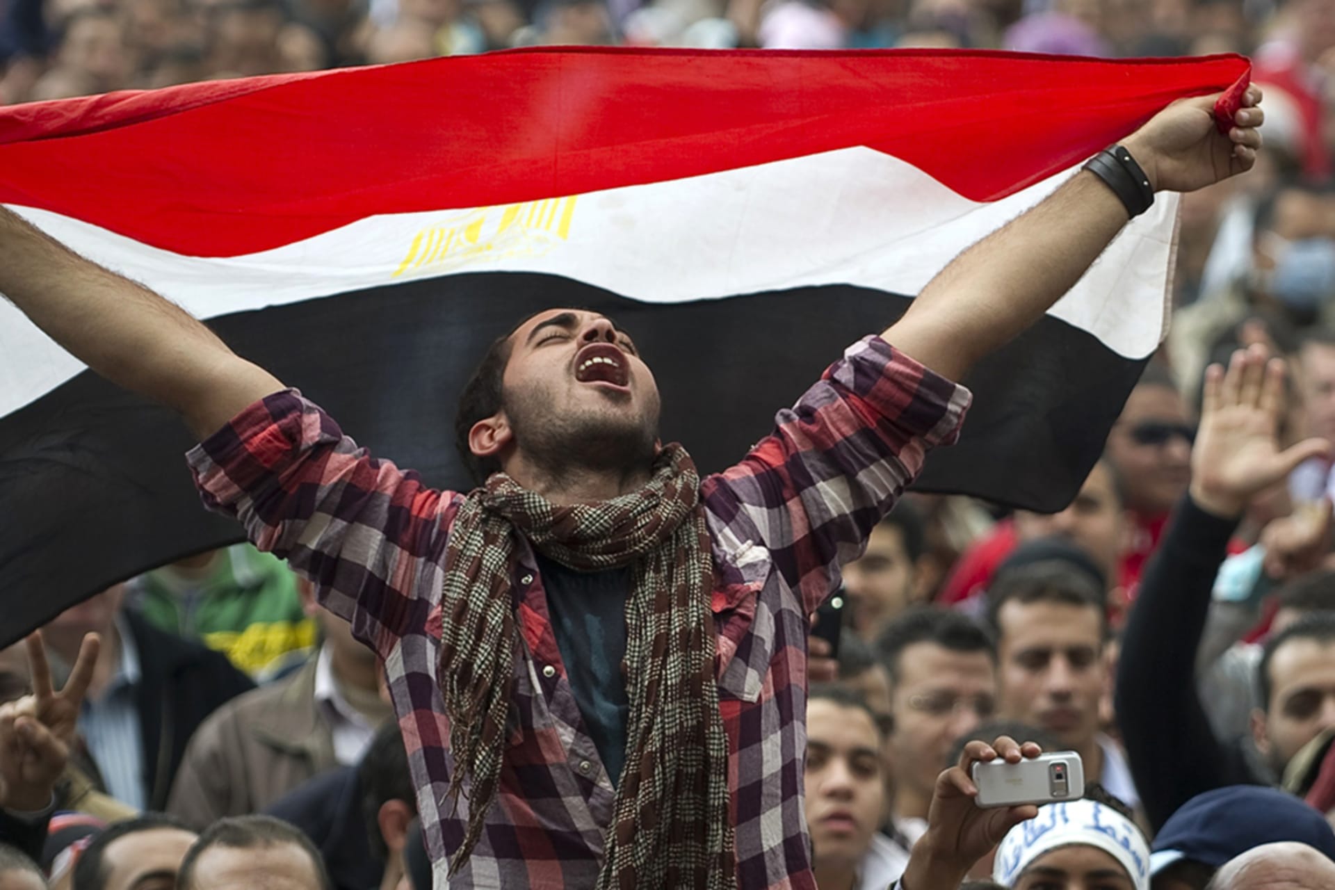<p>An Egyptian protester holds his national flag as he shouts slogans against President Hosni Mubarak at Cairo’s Tahrir Square in 2011.</p>
