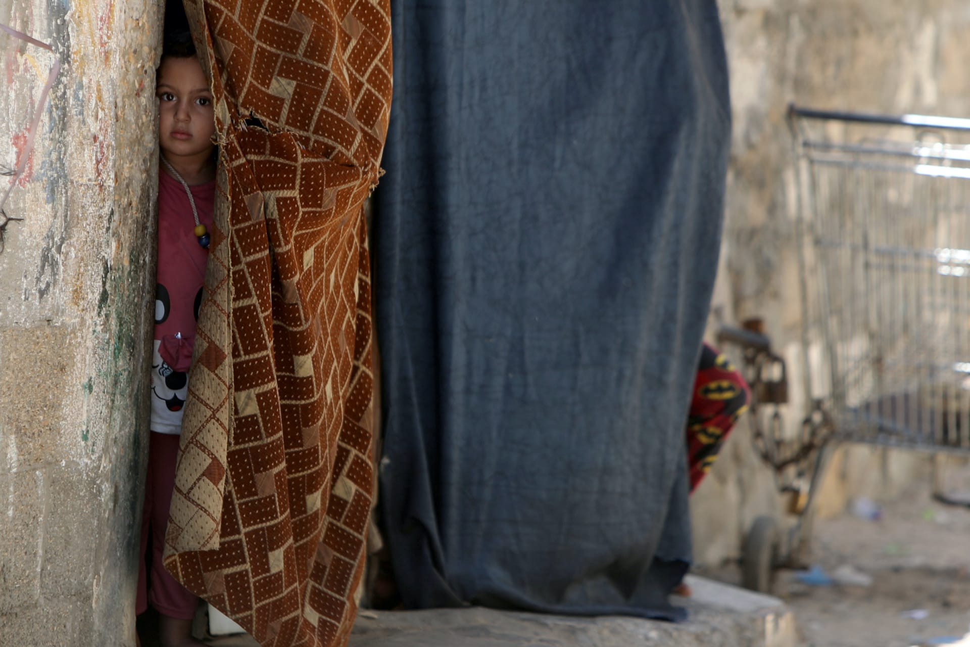<p>A Palestinian girl looks out of her family home as she watches members of Hamas security forces participating in a simulation exercise for preventing the spread of the coronavirus disease (COVID-19), in Gaza City July 18, 2020. REUTERS/Mohammed Salem</p>
