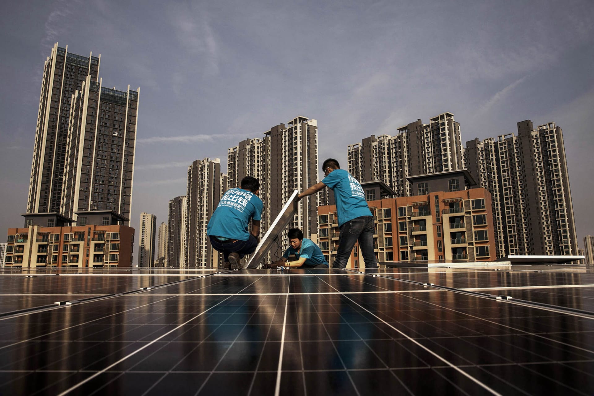 <p>Workers install solar panels on a building’s roof in China.</p>
