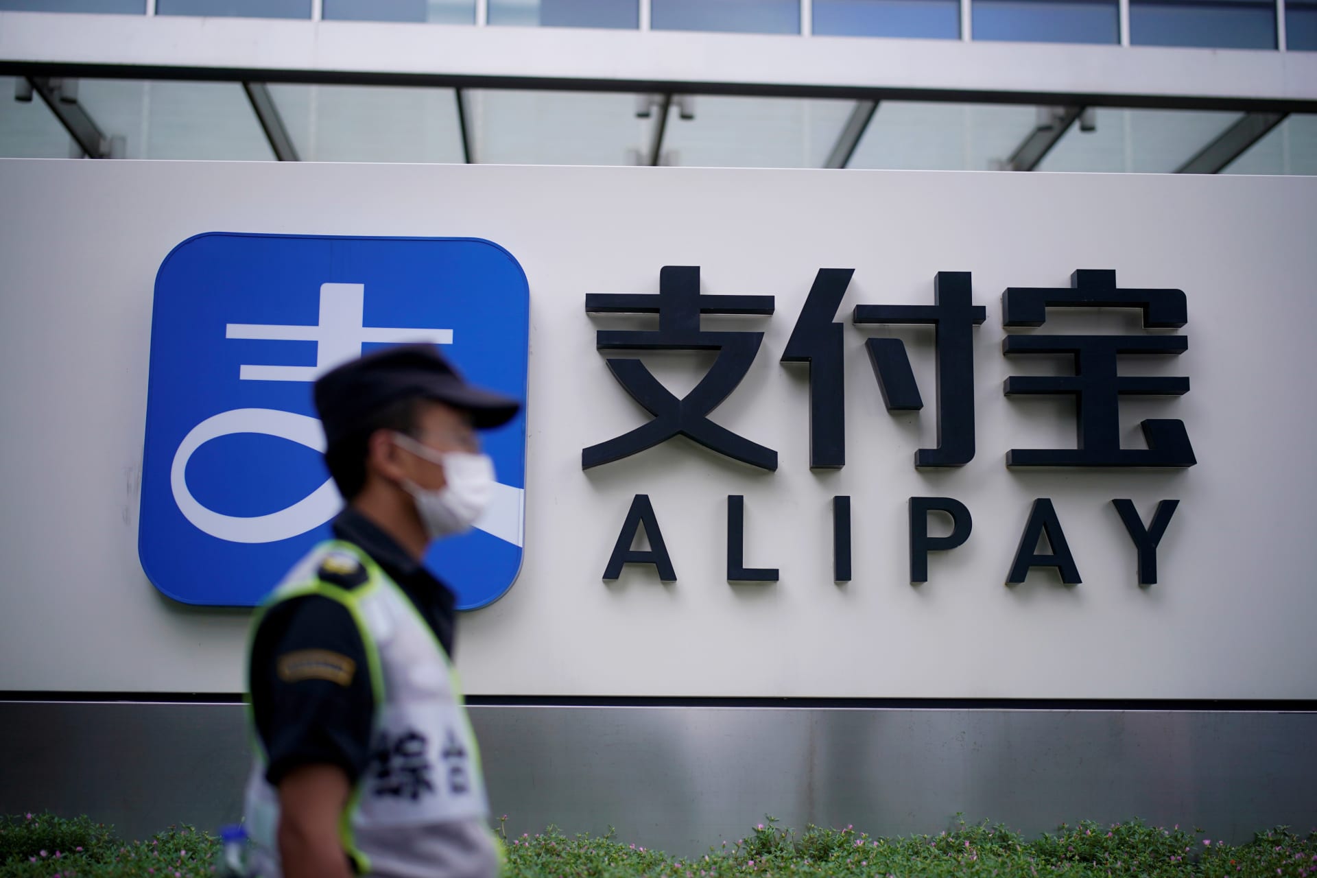 <p>A security guard walks past an Alipay logo at the office of Alipay.</p>
