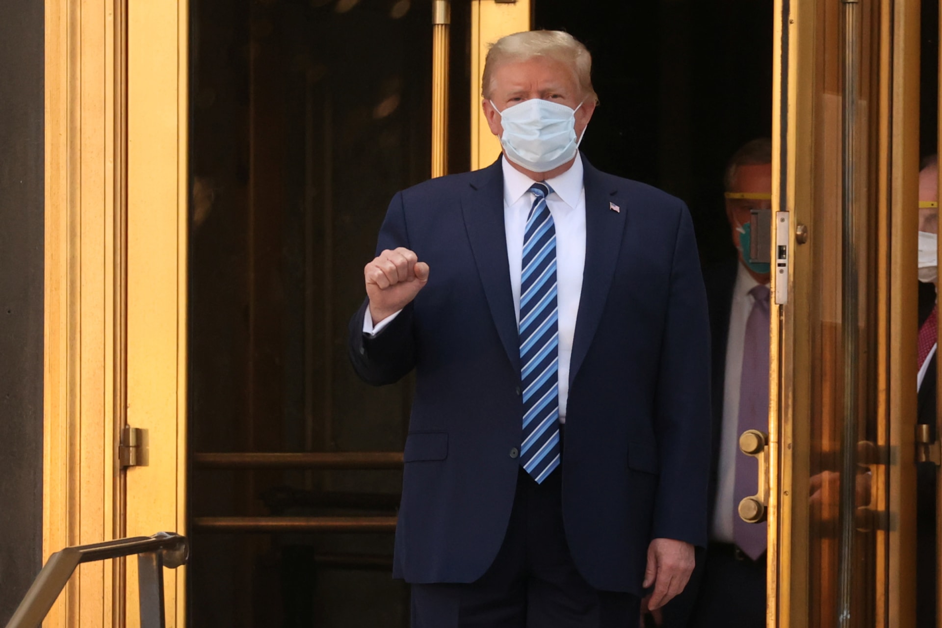 <p>U.S. President Donald Trump makes a fist as he walks out the front doors of Walter Reed National Military Medical Center after a fourth day of treatment for the coronavirus disease (COVID-19) as he heads to the Marine One helicopter on October 5, 2020.</p>
