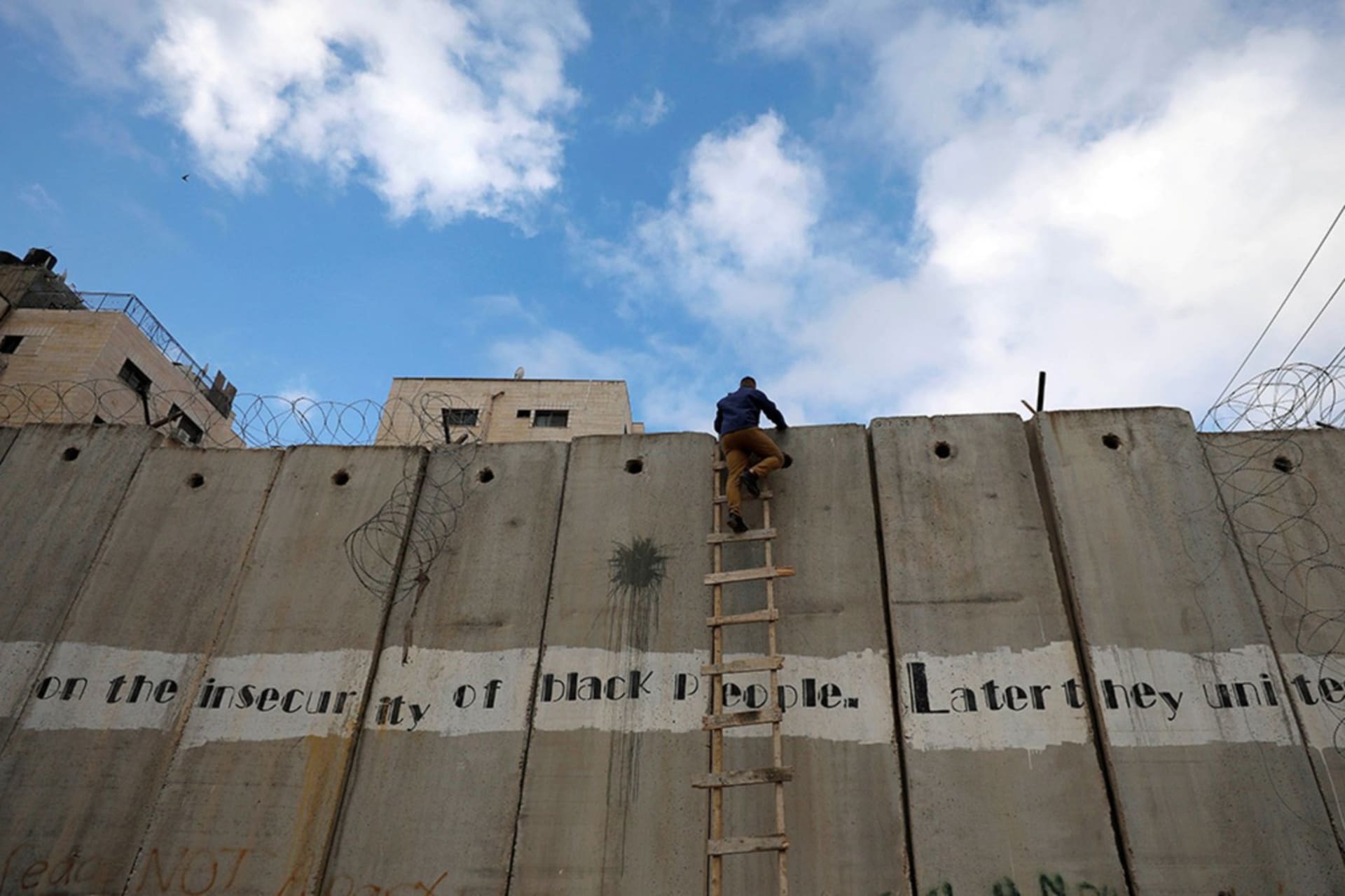 <p>A Palestinian climbs the Israeli barrier in the Israeli-occupied West Bank.</p>
