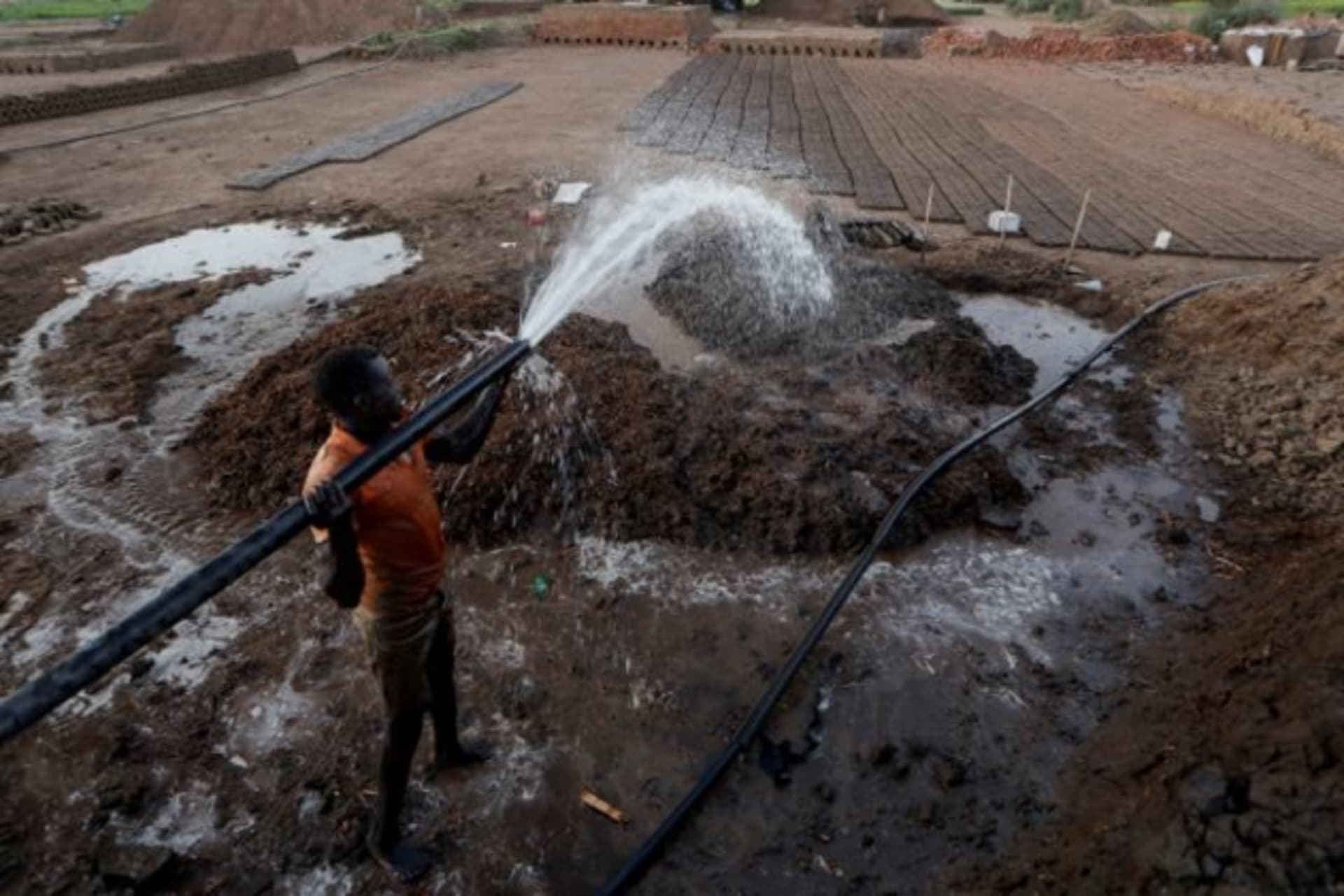 <p>Zaki El-Dine pours water from the Nile river onto a patch of mud to make bricks on Khartoum, Sudan on February 12, 2020. </p>
