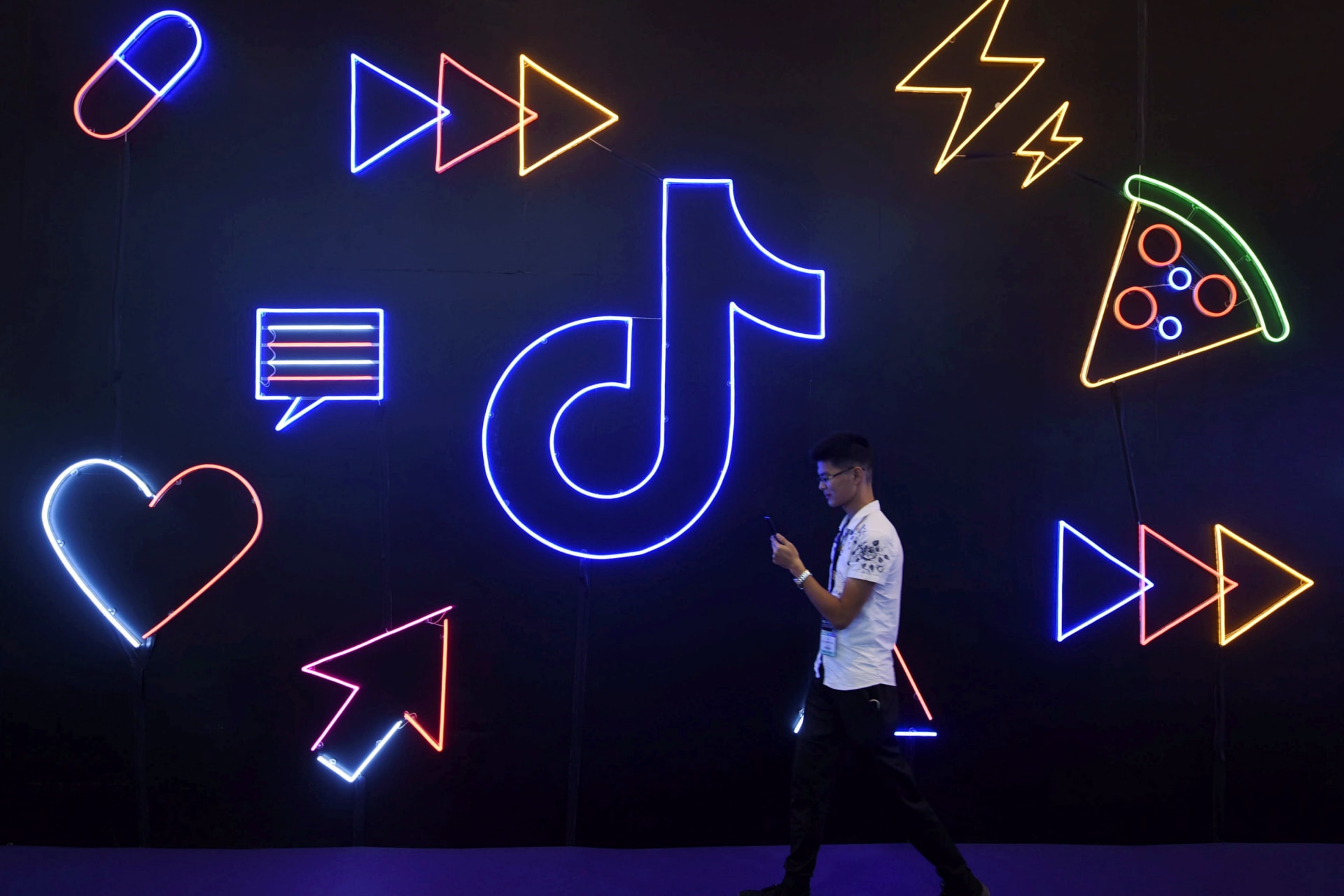 <p>A man holding a phone walks past a sign of Chinese company ByteDance’s app TikTok.</p>
