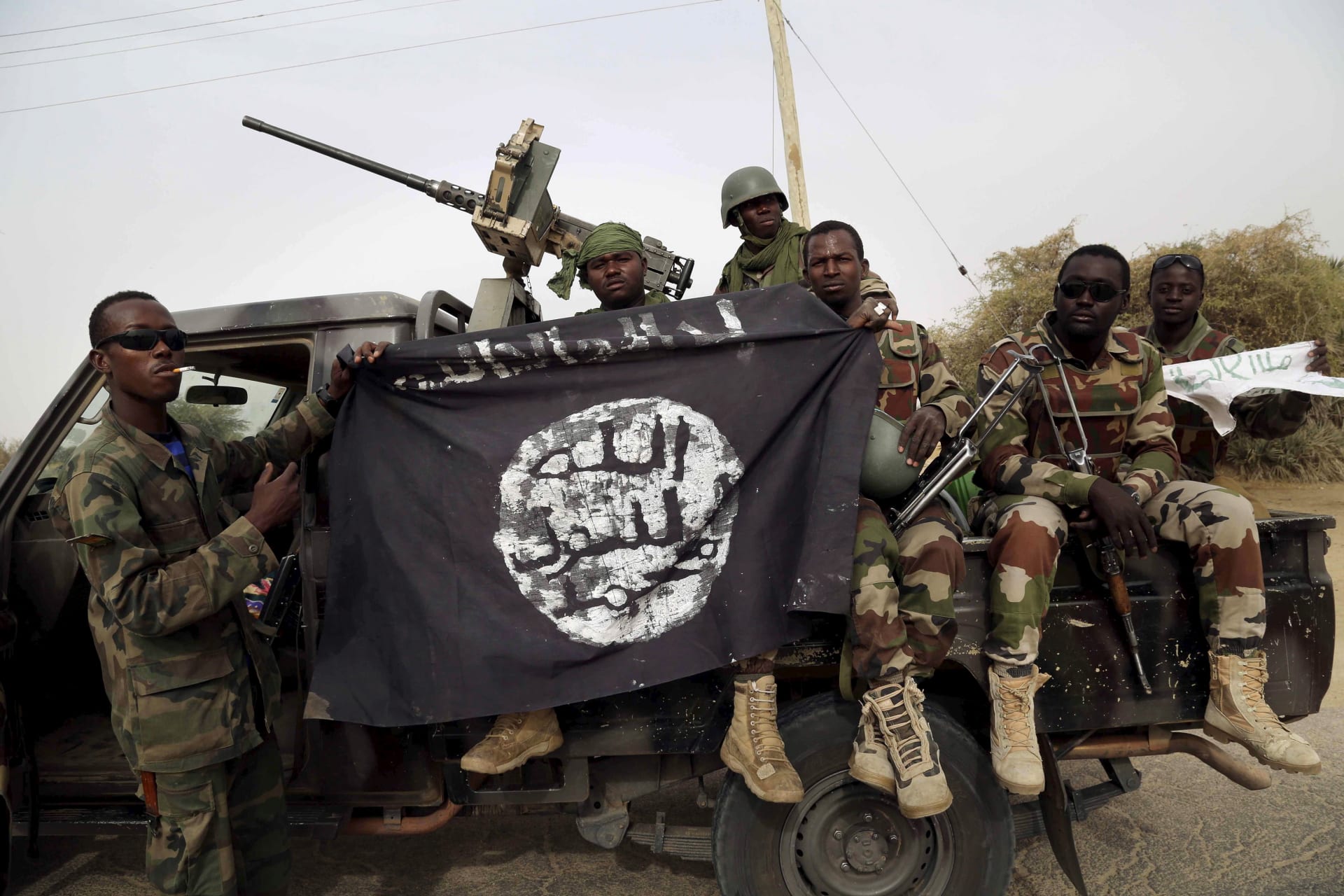<p>Nigerian soldiers hold up a Boko Haram flag that they had seized in the recently retaken town of Damasak, Nigeria, on March 18, 2015.</p>