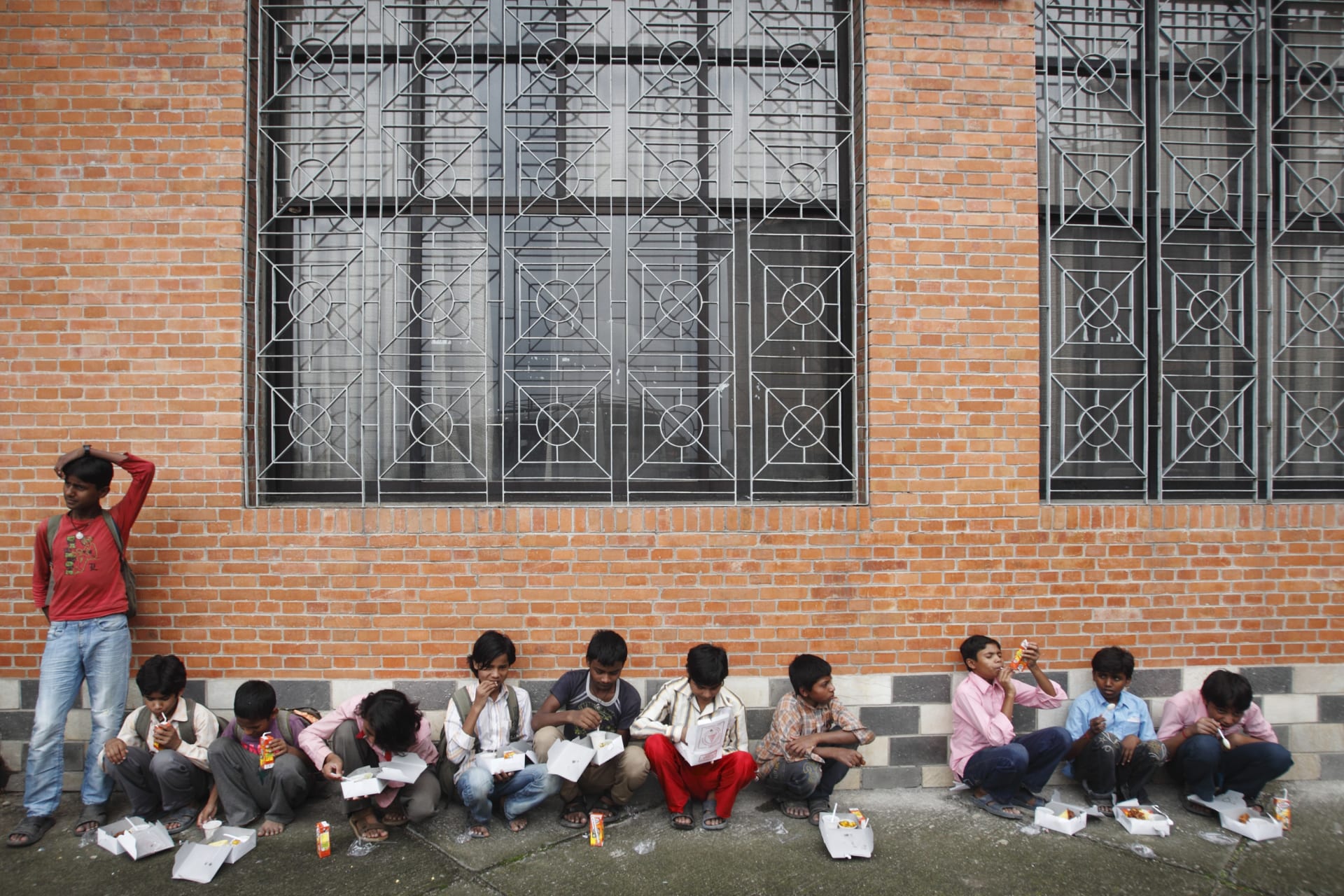 <p>Child laborers eat their lunch after being rescued from squalid working conditions a sari embroidery factory, with the help of Nepalese police and child rights organizations, near Kathmandu, 2012.</p>
