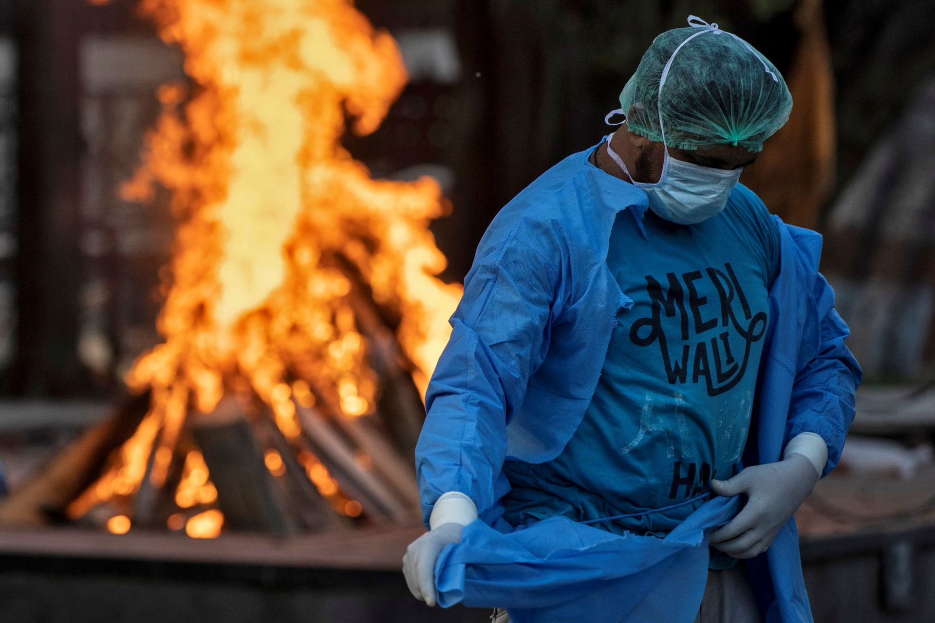 <p>An ambulance driver, Mohammad Aamir Khan, changes his personal protective equipment at a crematorium in New Delhi.</p>
