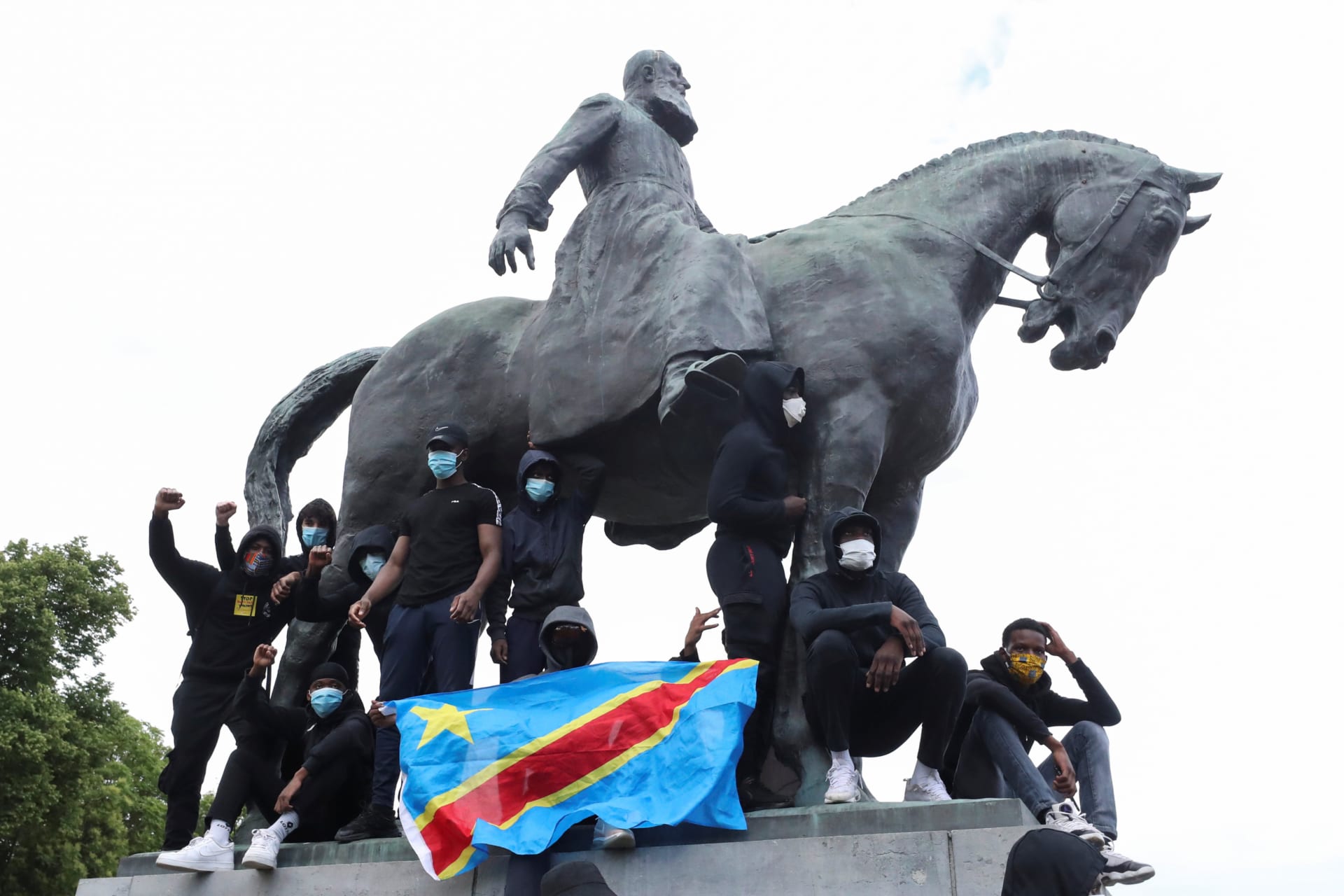 <p>Demonstrators stand on the statue of Leopold II as one of them holds a national flag of the Democratic Republic of Congo during a protest, organised by Black Lives Matter Belgium, in Brussels, Belgium, on June 7, 2020.</p>
