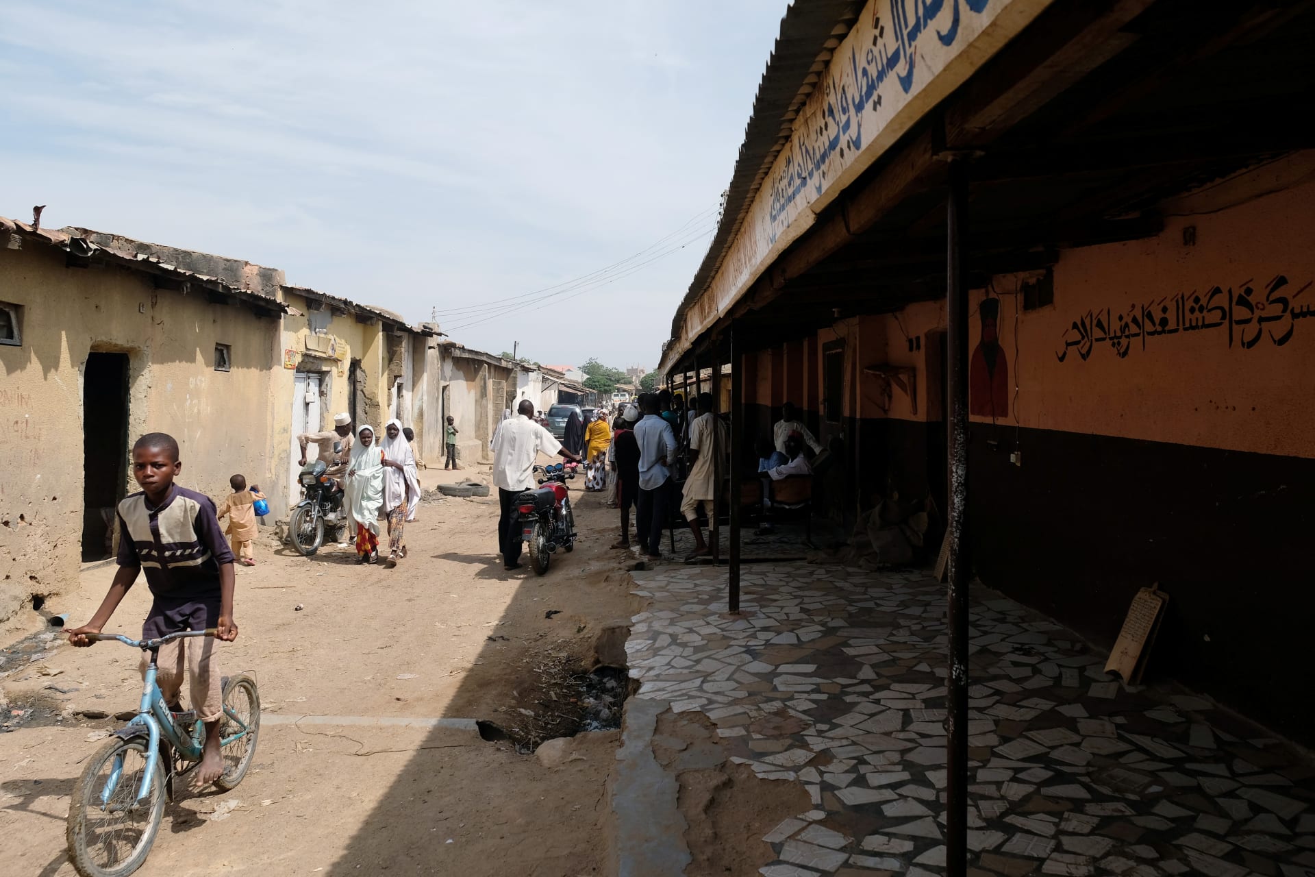 <p>People pass by the site of Mallam Nigas’s Islamic school and rehabilitation center, which was raided by police last week, in Katsina, Nigeria, on October 18, 2019.</p>