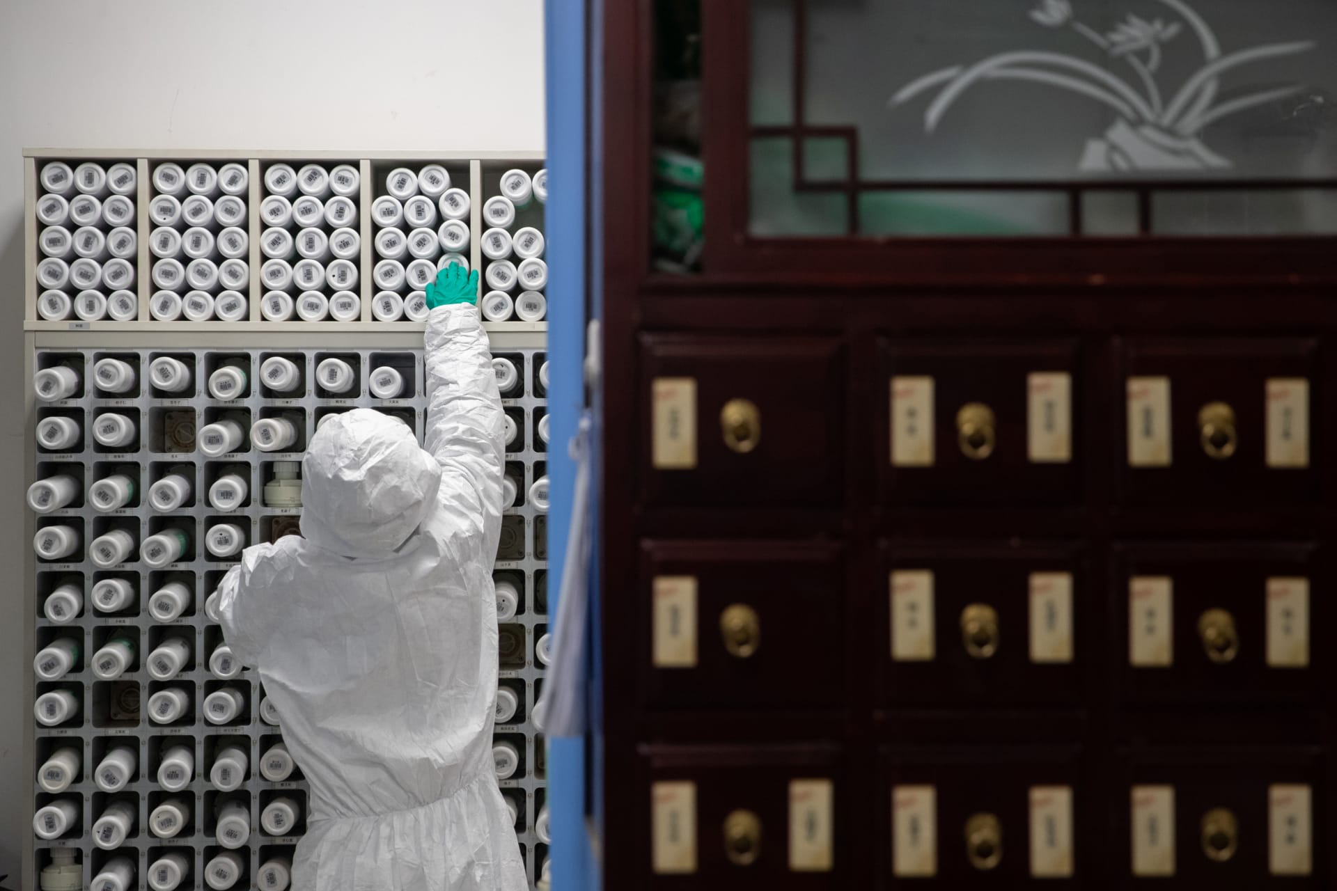 <p>A medical worker in protective suit prepares traditional Chinese medicine (TCM) for patients of the novel coronavirus with an intelligent dispensing equipment at a pharmacy in Wuhan, China on March 2, 2020.</p>
