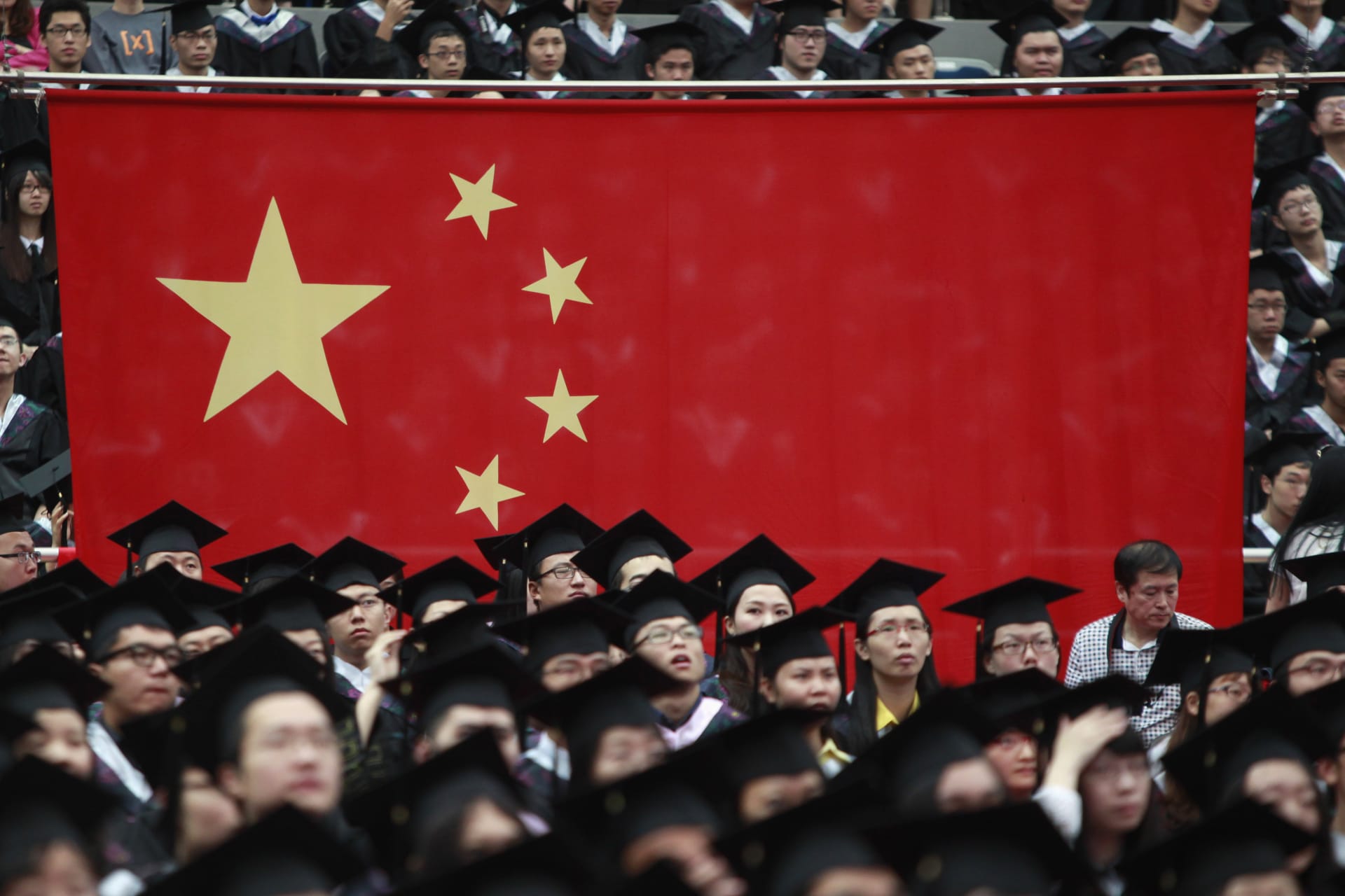 <p>Graduates set next to the Chinese flag during a graduation ceremony.</p>
