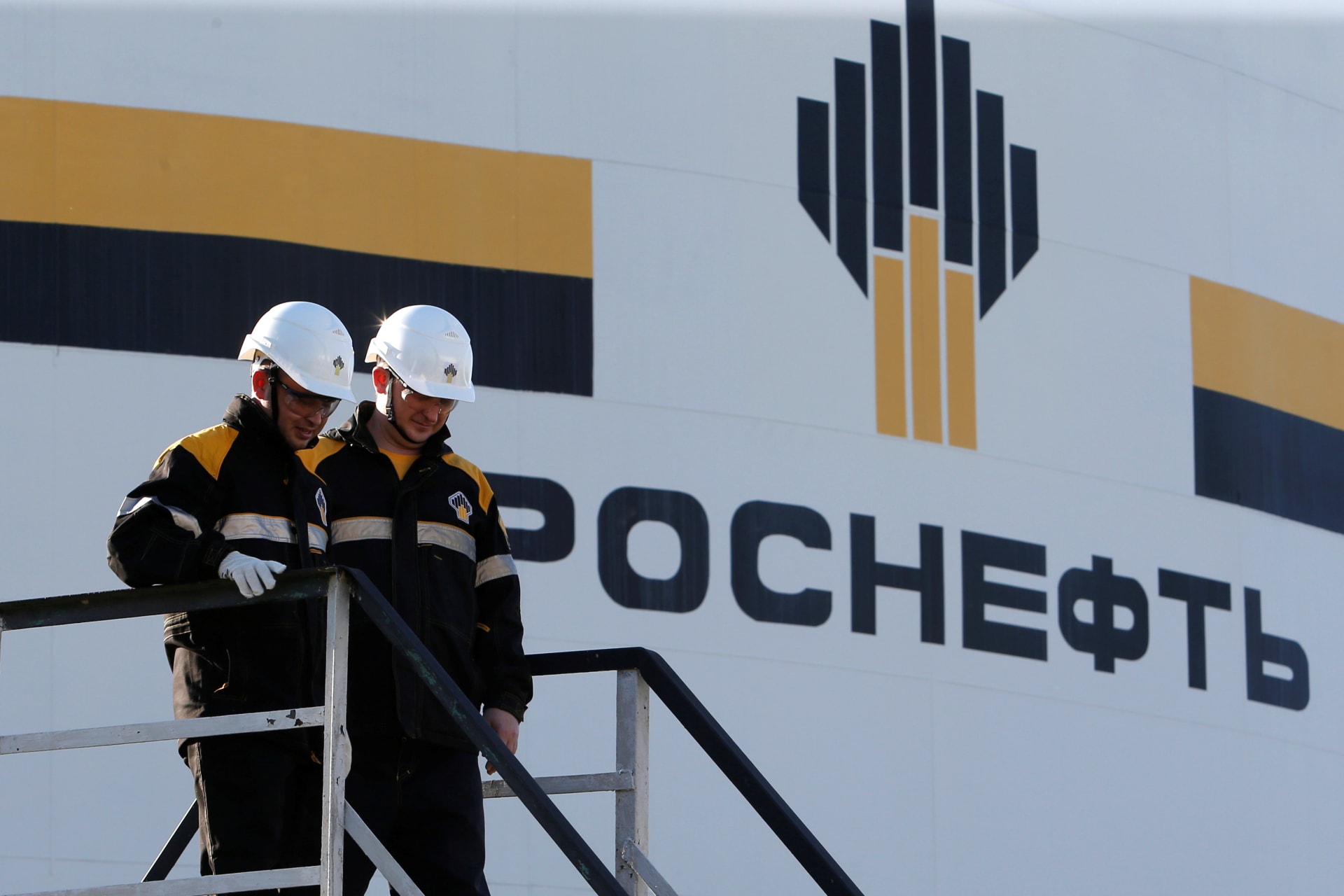 <p>Workers stand next to a logo of Russia’s Rosneft oil company at the central processing facility of the Rosneft-owned Priobskoye oil field outside the West Siberian city of Nefteyugansk, Russia.</p>
