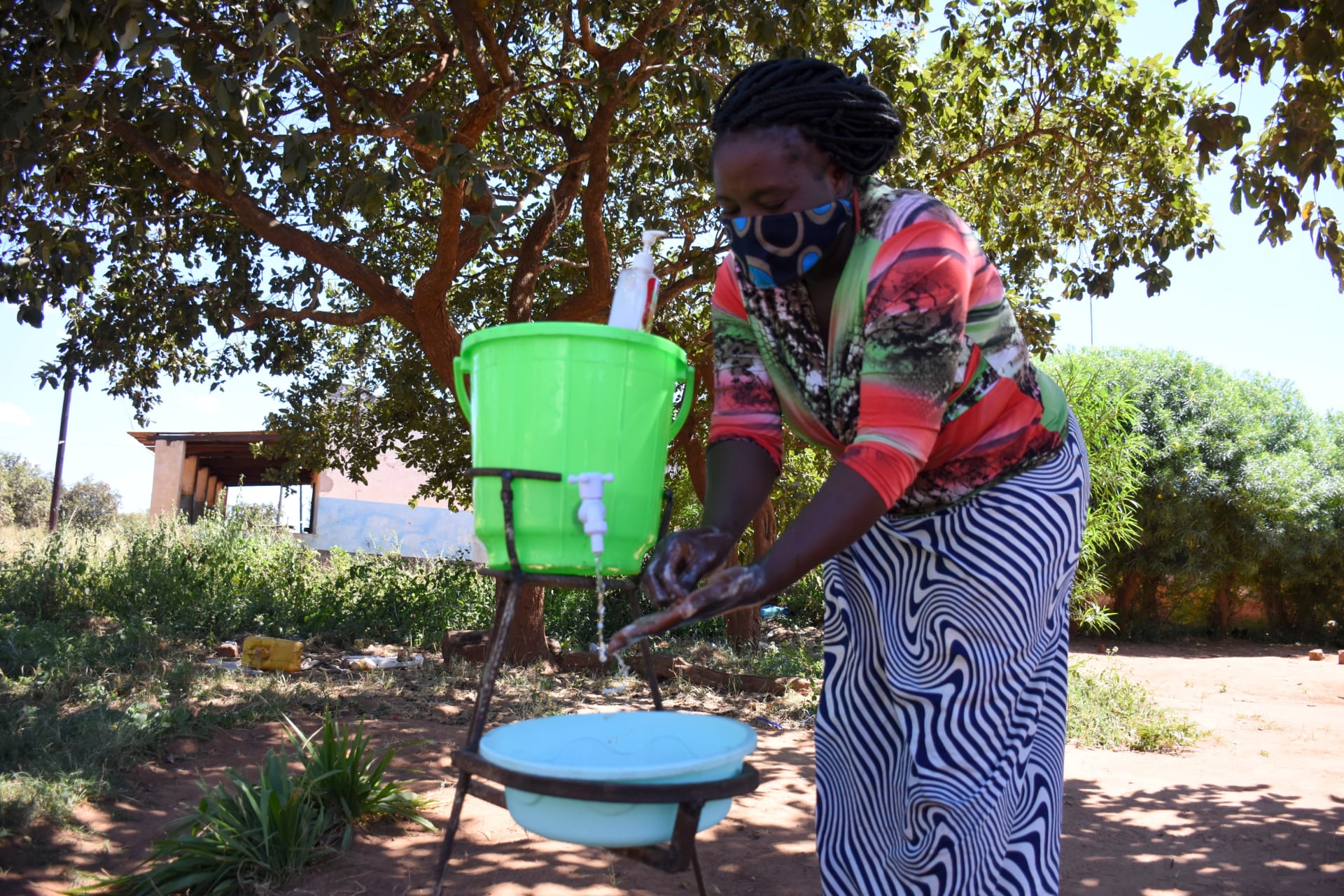 <p>Farmer Leticia Kangwa uses a hand washing station she installed outside her home after learning about how to prevent the spread of COVID-19, in April 2020, in Zambia.</p>
