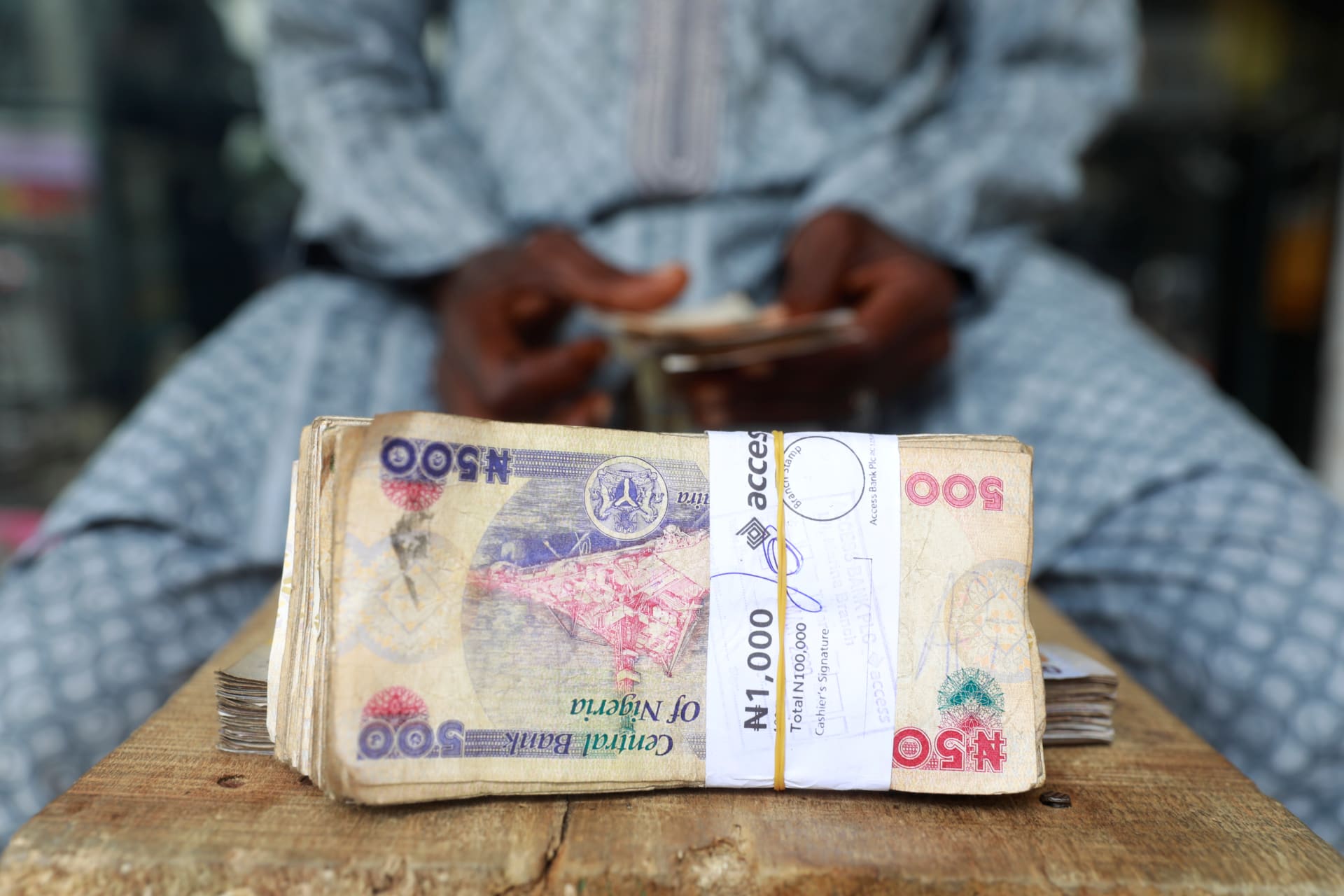 <p>A money changer counts Nigerian currency notes for a customer in Nigeria’s commercial capital, Lagos, Nigeria, on March 16, 2020.</p>
