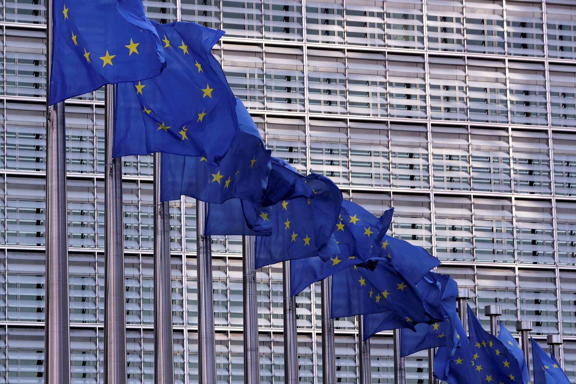 <p>European Union flags fly outside the European Commission headquarters.</p>